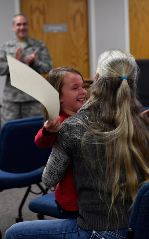 Samantha Clouse, a storm trooper, hugs her mother, Amanda, after receiving her certificate, for remaining calm, focused and ready during Hurricane Matthew, during a Storm Troopers ceremony at the Airman and Family Readiness Center here, Dec. 8, 2016. Nearly 23,000 base employees and their families evacuated Charleston Oct. 5, leaving a ride-out team of approximately 400 members to continue the base’s mission.