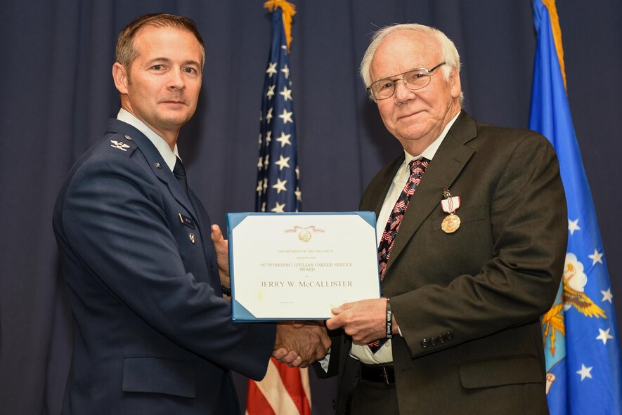 Col. Thaddeus Allen, the Air Force Special Operations Command operations division chief, presents Jerry McCallister, the AFSOC operations division deputy chief, the Outstanding Civilian Career Service Award during a retirement ceremony, at Hurlburt Field, Fla., Dec. 9, 2016. McCallister retired from the civil service after 30 years. He also served 23 years on active duty bring his total service to the Air Force to 53 years. (U.S. Air Force photo by Senior Airman Jeff Parkinson)