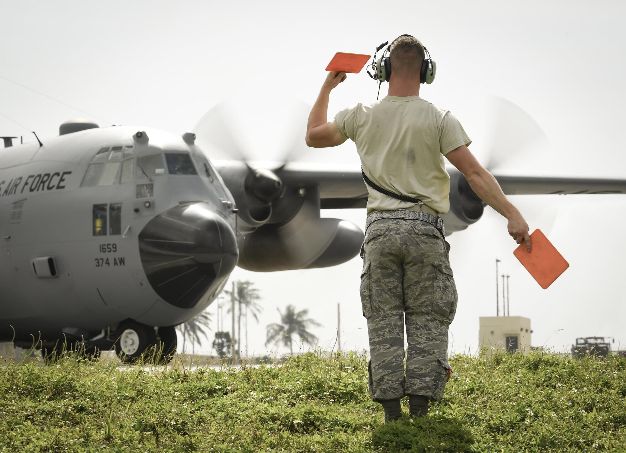Senior Airman Benjamin Campanella, 374th Maintenance Squadron crew chief, marshals a C-130H Hercules for takeoff at Andersen Air Force Base, Guam, Dec. 7, 2016. C-130s are ideal for performing air drops like those conducted during OCD because they are large enough to carry cargo and small enough to maneuver at relatively low altitudes. (U.S. Air Force photo by Senior Airman Elizabeth Baker/Released)
