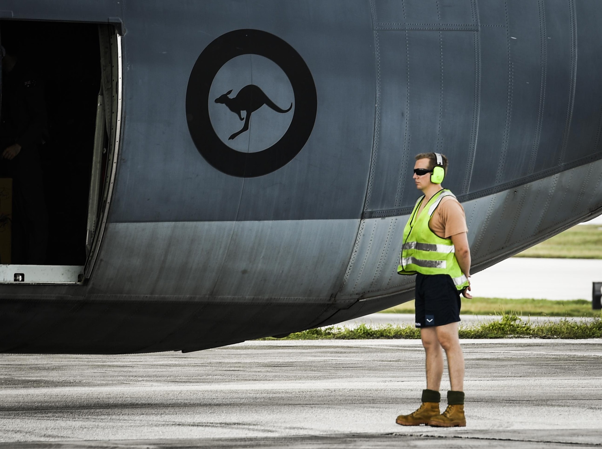A maintainer with the Royal Australian Air Force waits to marshal a C-130J Super Hercules for takeoff during Operation Christmas Drop at Andersen Air Force Base, Guam, Dec. 7, 2016. The RAAF sent a C-130J to OCD to train with the 36th Airlift Squadron and the Japan Self Defense Force, helping participants understand each other’s techniques and giving them a chance to offer each other insight. Bilateral training improves participants’s abilities to work together during real world scenarios, such as delivering disaster relief supplies.(U.S. Air Force photo by Senior Airman Elizabeth Baker/Released)