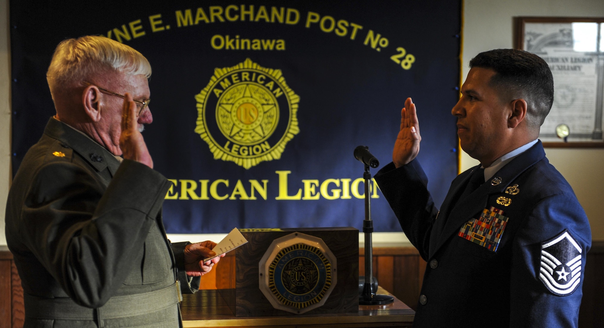 Retired United States Marine Corps Maj. John Glenn reenlists Master Sgt. Thundercloud Hirajeta. Dec. 2, 2016, at the American Legion Wayne E. Marchand post on Okinawa, Japan. Not only did Glenn officiate Hirajeta’s reenlistment, he has now done his original enlistment and another reenlistment ceremony and plans to retire him as well. (U.S. Air Force photo by Airman 1st Class Nick Emerick/Released) 