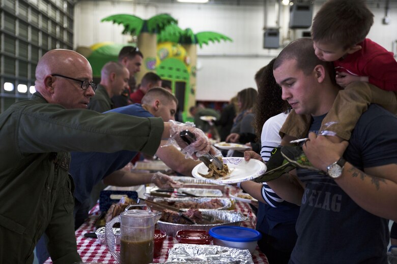 Gunnery Sgt. Matthew Viehl, assistant chief of operations with Aircraft Rescue and Firefighting serves food to a fellow Marine and his son during the Christmas dinner at Marine Corps Air Station Iwakuni, Japan, Dec. 10, 2016. ARFF holds the celebration annually to help spread holiday cheer to the orphans and to bring service members, their families and Japanese together. Marines volunteered their time and provided the children with a homemade, American meal. (U.S. Marine Corps photo by Lance Cpl. Gabriela Garcia-Herrera)