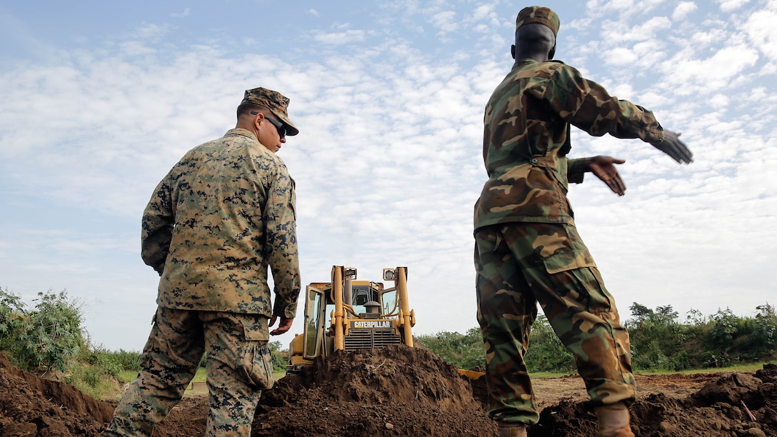 Cpl. Andrew Bastian, a heavy equipment advisor with Special Purpose Marine Air-Ground Task Force Crisis Response-Africa, stands on the berm a soldier with the Uganda People’s Defense Force creates with a bulldozer at Camp Singo, Uganda, Nov. 16, 2016. Marines with SPMAGTF-CR-AF taught classes and participated in practical application exercises with UPDF soldiers during the nine-week training mission.