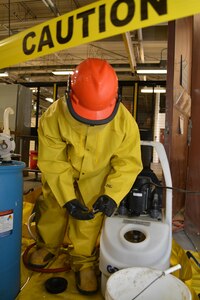 Seaman Marcell Rainey uses a test strip to check the pH at the pump tank cap while cleaning a U-bend heat exchanger at Southeast Regional Maintenance Center (SERMC). Nov. 16th. The cleaning fluid is cycled through the heat exchanger for at least three consecutive pH neutral tests, then flushed with fresh water. (Photo by Scott Curtis)