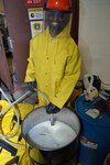 Seaman Marcell Rainey flushes the U-bend heat exchanger into a pre-staged hazardous waste disposal drum while descaling a marine heat exchanger at Southeast Regional Maintenance Center (SERMC) Nov. 16th. The solution is neutralized with soda ash or baking soda to neutralize the acid. 