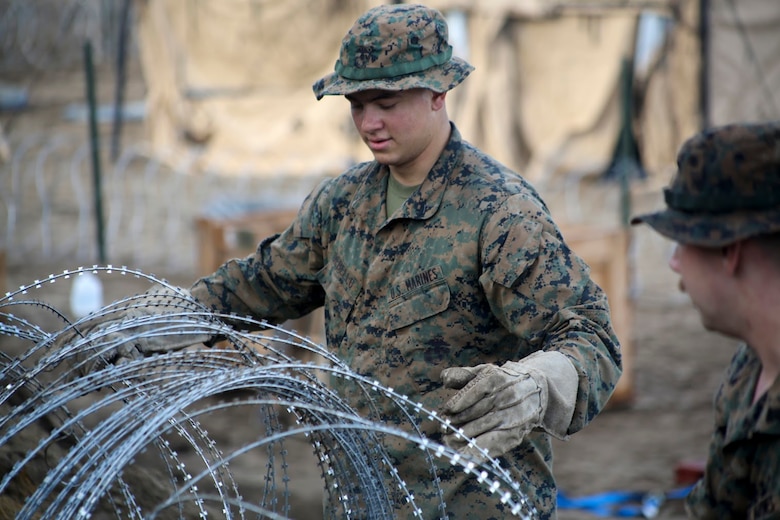 Lance Cpl. Travis Debello places concertina wire during a field exercise aboard Marine Corps Auxiliary Landing Field Bogue, N.C, Nov. 30, 2016. Marines assigned to Marine Wing Support Squadron 271, Marine Aircraft Group 14, 2nd Marine Aircraft Wing placed concertina wire around the perimeter of their encampment to fortify security like they would for a forward operating base in a deployed setting. Debello is a combat engineer assigned to Engineer Company, MWSS-271. (U.S. Marine Corps photo by Sgt. N.W. Huertas/ Released) 