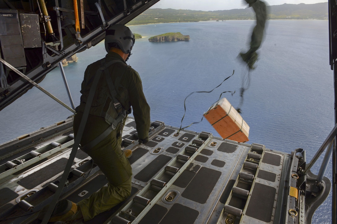 Air Force Senior Airman Anthony Schoof releases a bundle from the back of a C-130 Hercules during Operation Christmas Drop over the Micronesian islands, Dec. 5, 2016. Schoof is a loadmaster assigned to the 36th Airlift Squadron. Air Force photo by Senior Airman Elizabeth Baker