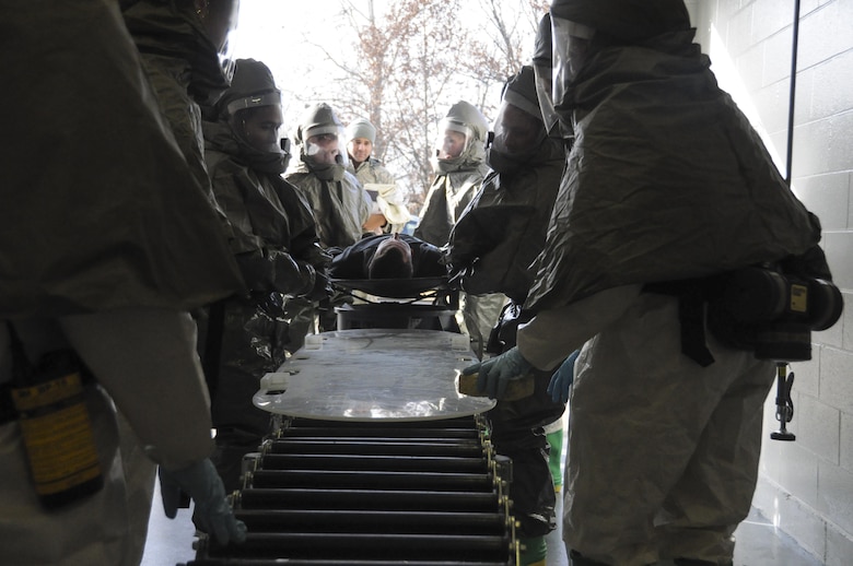 U.S. Air Force Airmen assigned to the 509th Bomb Wing carry a volunteer victim on a litter to an in-place patient decontamination line where medical personnel assigned to the 131st BW and 442nd Fighter Wing simulate washing and drying the victims during a total force mass casualty exercise at Whiteman Air Force Base, Mo., Dec. 3, 2016. During the decontamination process, medical personnel remove and bag the victim's clothing, wash them, and test their skin for contaminants with M8 chemical detection paper before drying them. (U.S. Air Force photo/Senior Airman Missy Sterling)