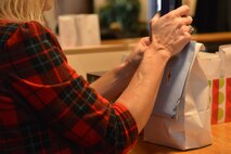 A volunteer from the Officer’s Spouses Club staples a card to a cookie bag at the annual Airman’s Cookie Drive at Minot Air Force Base, N.D., Dec. 9, 2016. The cards were handwritten by Edgewood Vista retirement home, donated by the American Red Cross and delivered to Team Minot Airmen before the holidays.  (U.S. Air Force photo/Airman 1st Class Jessica Weissman)