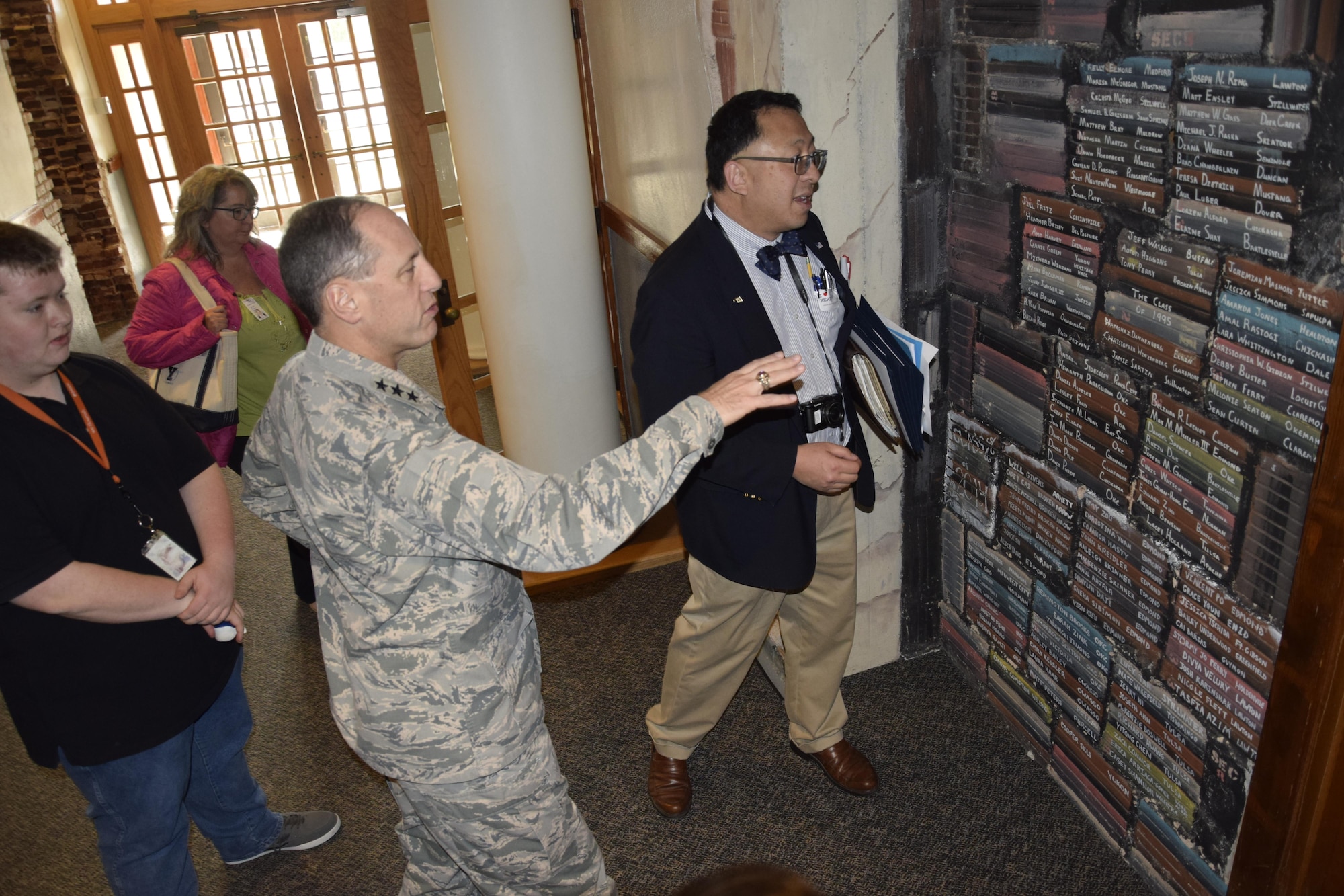 Air Force Sustainment Center Commander Lt. Gen. Lee K. Levy II, center, motions toward a wall with the names of graduates from the Oklahoma School of Science and Mathematics while OSSM President Dr. Frank Y.H. Wang notes the success of particular students shown on the wall inside the Dr. Edna McDuffie Manning Academic Center. General Levy toured the school Dec. 1 to learn about the school’s programs while personally engaging the students to foster better understanding of the opportunities for STEM careers in AFSC and the Air Force. (U.S. Air Force photo/Greg L. Davis)