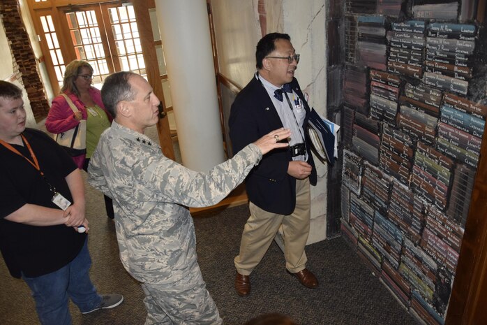 Air Force Sustainment Center Commander Lt. Gen. Lee K. Levy II, center, motions toward a wall with the names of graduates from the Oklahoma School of Science and Mathematics while OSSM President Dr. Frank Y.H. Wang notes the success of particular students shown on the wall inside the Dr. Edna McDuffie Manning Academic Center. General Levy toured the school Dec. 1 to learn about the school’s programs while personally engaging the students to foster better understanding of the opportunities for STEM careers in AFSC and the Air Force. (U.S. Air Force photo/Greg L. Davis)