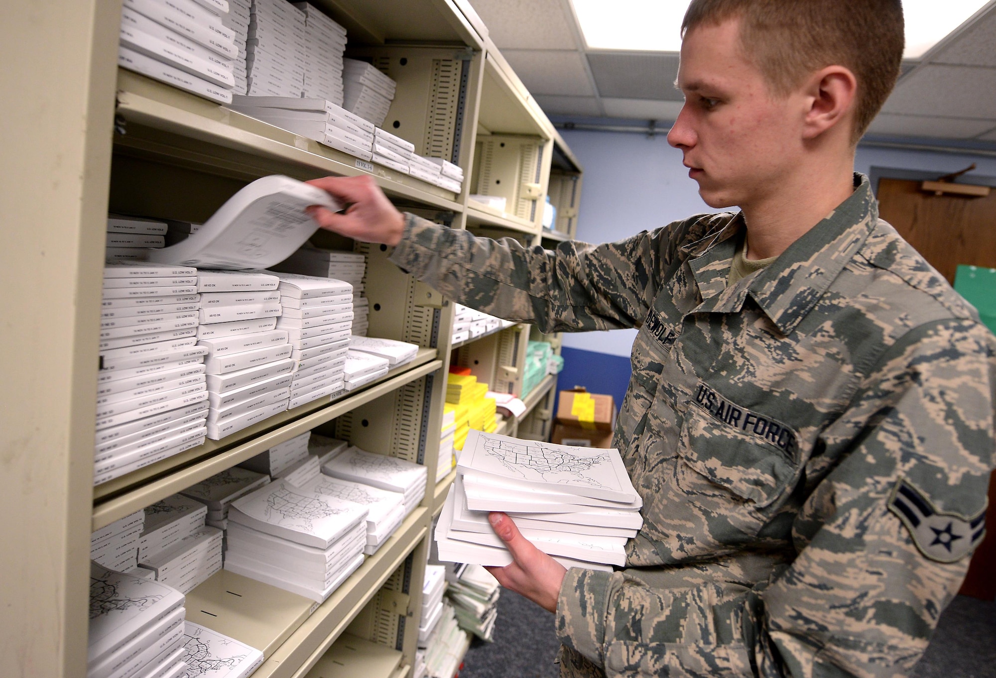 Airman 1st Class Maxim Dewolf, a combat crew communications apprentice assigned to the 55th Operations Support Squadron, builds a flight information publications bag for an Offutt mission Nov. 30, 2016 at Offutt Air Force Base, Neb. These paper publications will soon be replaced with digital versions loaded on Apple iPads as Offutt begins utilizing electronic flight bags. (U.S. Air Force photo by Delanie Stafford)