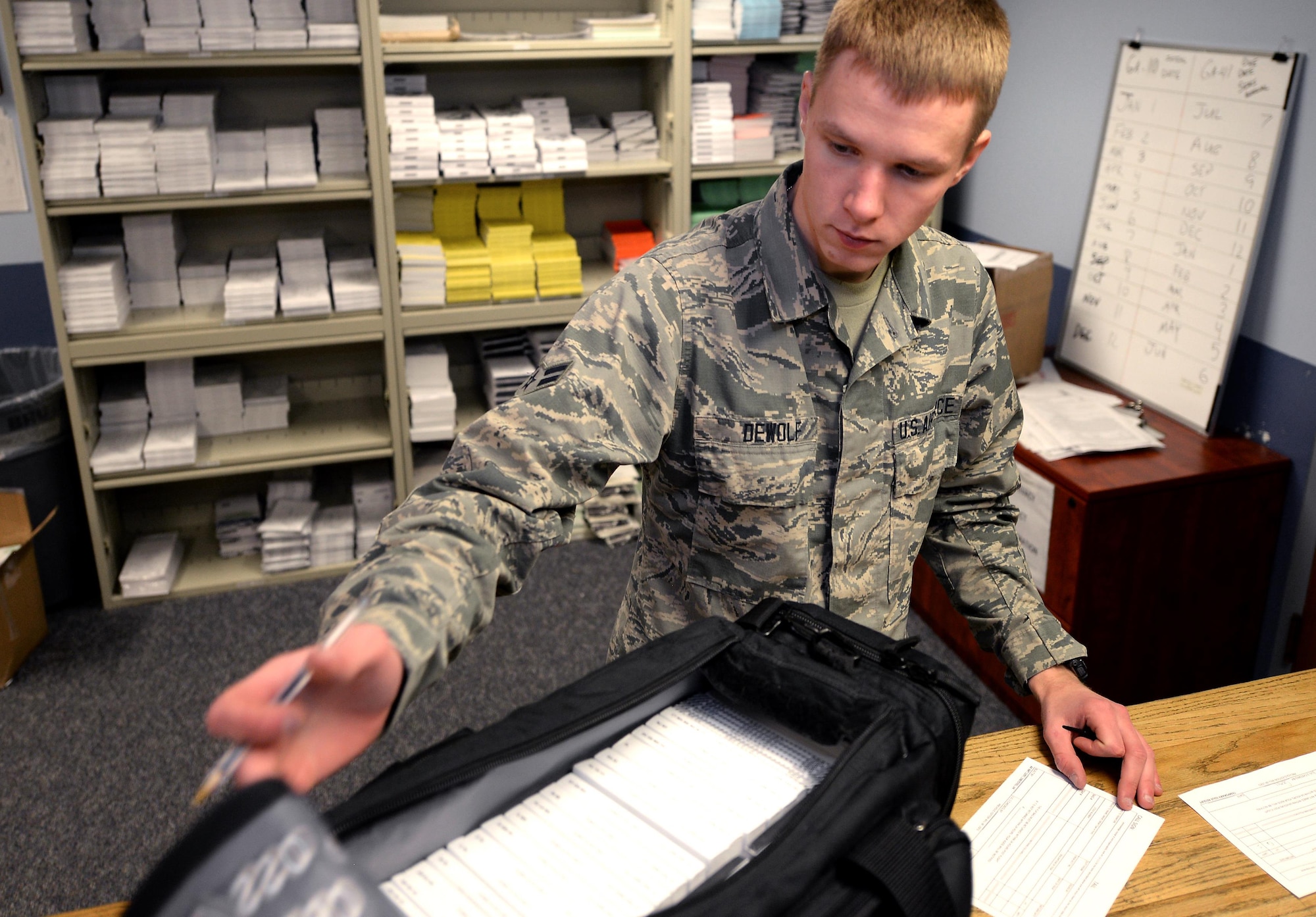 Airman 1st Class Maxim Dewolf, a combat crew communications apprentice assigned to the 55th Operations Support Squadron, builds a flight information publications bag for an Offutt mission Nov. 30, 2016 at Offutt Air Force Base, Neb. These paper publications will soon be replaced with digital versions loaded on Apple iPads as Offutt begins utilizing electronic flight bags. (U.S. Air Force photo by Delanie Stafford)