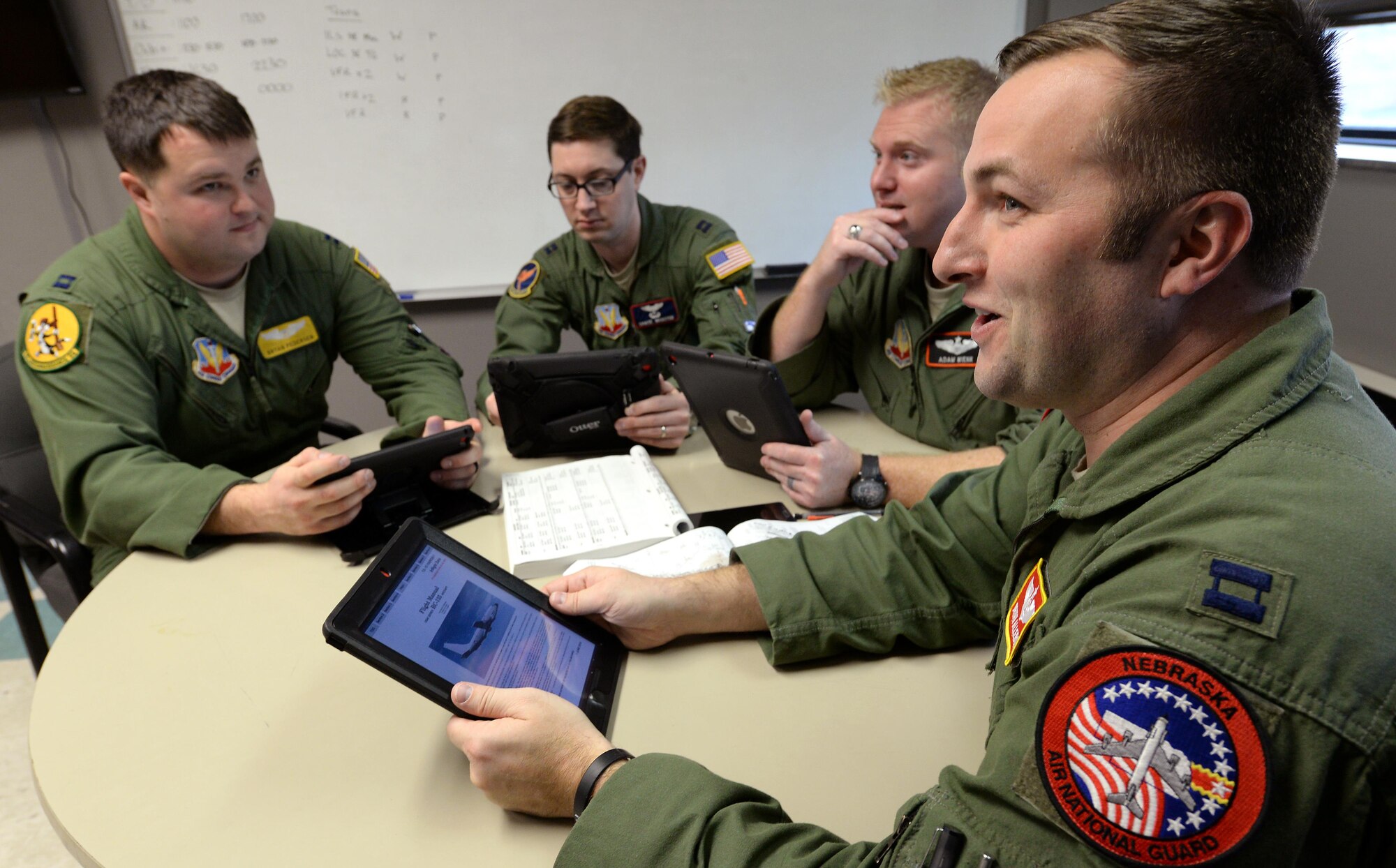 Capt. Bryan Allebone (right), an instructor navigator and fulltime Air National Guard member assigned to the 238th Combat Training Squadron, does mission planning with other Offutt aircrew members Dec. 12, 2016 at Offutt Air Force Base, Neb. The crew members are using electronic flight bags on Apple iPads that have replaced much of the legacy paper processes. Allebone coordinated efforts to get an EFB program approved and stood up at Offutt. (U.S. Air Force photo by Delanie Stafford)