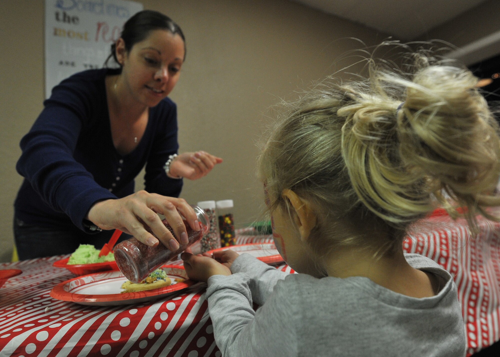 U.S. Air Force Staff Sgt. Victoria Cameron, 325th Maintenance Squadron munitions operations supervisor, sprinkles candy into a child's hands during the annual Hearts Apart event in Panama City, Fla., Dec. 3, 2016. Guests in attendance were welcomed with Christmas themed décor and other holiday related activities. (U.S. Air Force photo by Senior Airman Ty-Rico Lea/Released)