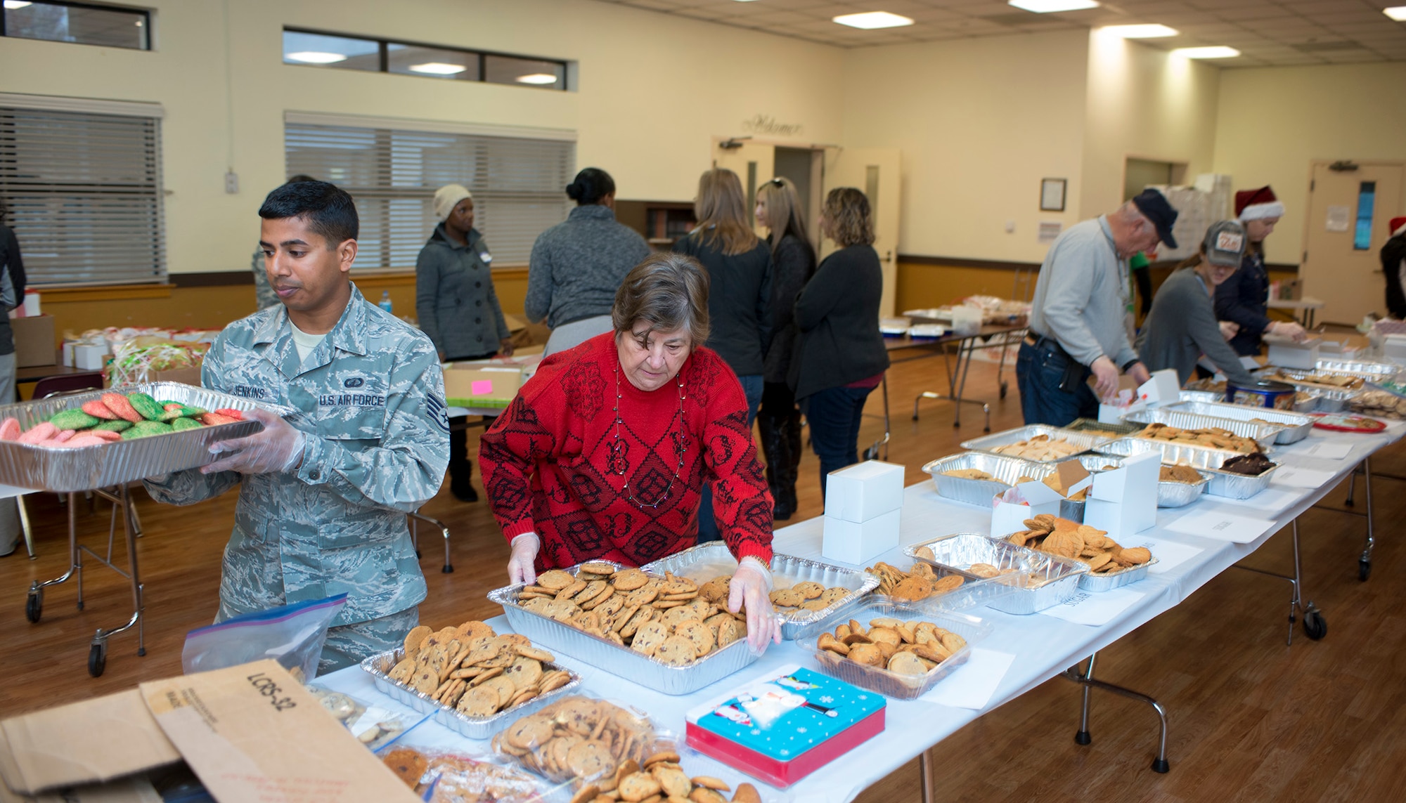 Staff Sgt. Nicholas Jenkins, 60th Mission Support Group, and Ida Aquilina, prepare trays of freshly baked cookies for distribution during Operation Cookie Drop at Travis Air Force Base, Calif., Dec. 7, 2016. Hundreds of volunteers participated in this year’s event by baking, sorting, packaging and delivering thousands of cookies to Travis Airmen. (U.S. Air Force Photo/T.C. Perkins Jr.)