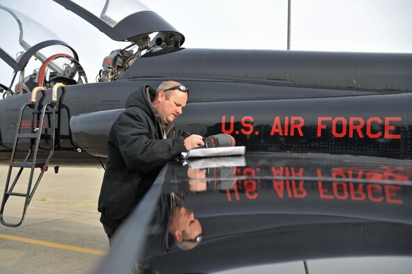 Matt Miller, 9th Maintenance Group T-38 aircraft mechanic, completes a maintenance checklist while inspecting a T-38 Talon Dec. 5, 2016, at Beale Air Force Base, California. The T-38 aircraft mechanics document all of the maintenance performed on the aircraft. (U.S. Air Force Photo/Airman Tristan D. Viglianco)