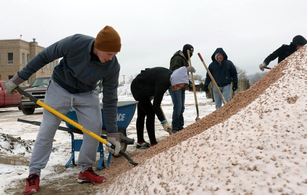 Ellsworth Airmen shovel gravel to encase piping for a new Habitat for Humanity home in Rapid City, S.D., Dec. 10, 2016. The gravel dug by the volunteers helps prevent pipe damage by creating a stable foundation. (U.S. Air Force photo by Airman 1st Class Donald C. Knechtel)