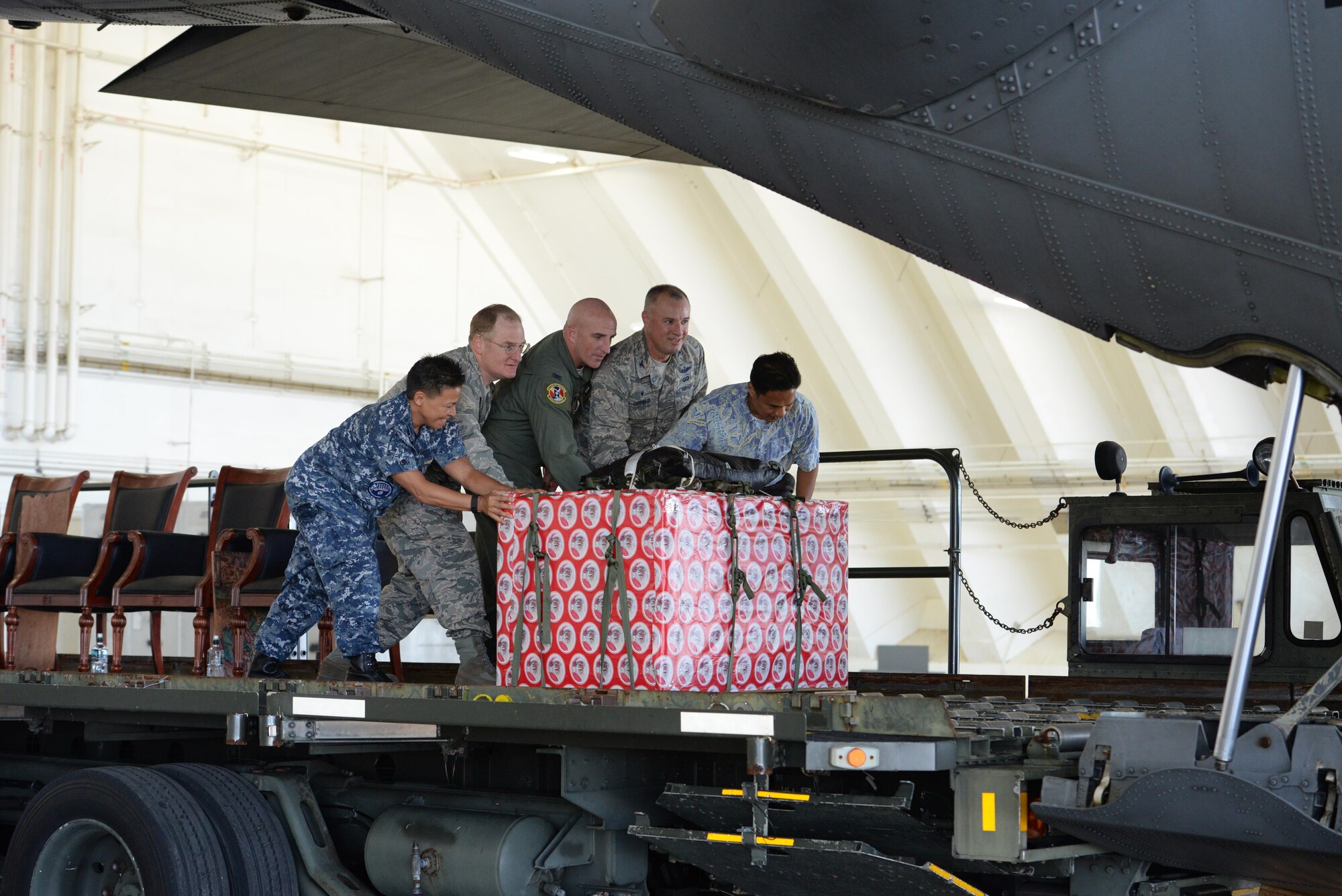 Leaders move a box of donated goods into the back of a C-130 Hercules during the 65th Operation Christmas Drop push ceremony at Andersen Air Force Base, Guam, Dec. 6, 2016. Left to right: Rear Admiral Bette Bolivar, commander, Joint Region Marianas, Brig. Gen. Douglas Cox, 367th Wing commander, Andersen AFB, Guam, Col. Kenneth Moss, 374th Airlift Wing commander, Yokota Air Base, Japan, Col. Scott Zippwald, 515th Air Mobility Operations Wing commander, Joint Base Pearl Harbor Hickam, Hawaii and Manny Hechanova, Associate Director of Telecommunications and Distance Education Operation at the University of Guam. Operation Christmas Drop is the longest running humanitarian airlift operation in the history of the Department of Defense, impacting the lives of more than 20,000 islanders. The people of the Micronesian islands can expect to see service members aboard a C-130 Hercules drop a box, attached to a parachute, filled with rice, fish hooks, educational materials, clothing and toys. (U.S. Air Force photo by Master Sgt. Theanne Herrmann)