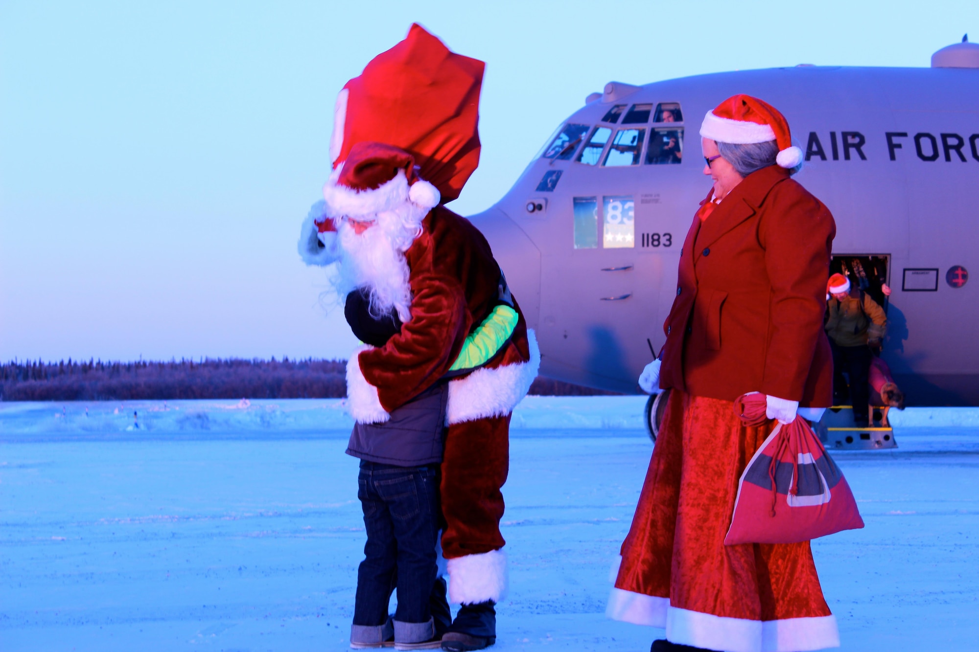 Mr. and Mrs. Claus embrace a local Akiachak child during Operation Santa Claus, Dec. 3, 2016. The 144th Airlift Squadron supported the mission, marking the final Operation Santa Claus flown by an Alaska National Guard C-130 Hercules. (U.S. Army National Guard photo by Capt. Amanda Plachek)