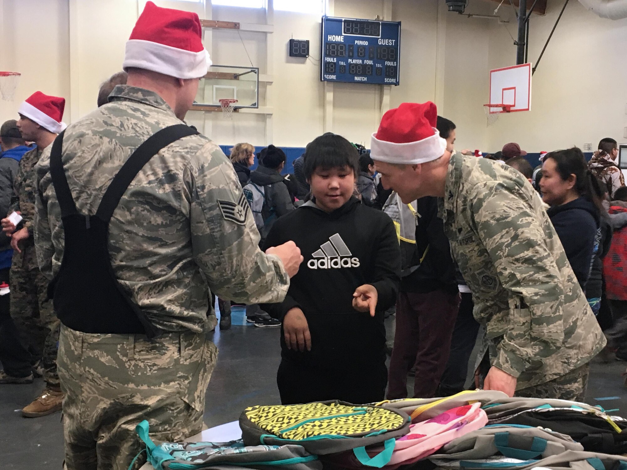 An Airman joins 176th Wing commander, Brig. Gen. Steve deMilliano to hand out backpacks to children in Akiachak Dec. 3, 2016 for Operation Santa Claus. The Alaska National Guard community relations program is an annual event in it's 60th year of visiting rural villages throughout the state. (U.S. Air National Guard photo by Lt. Col. Candis Olmstead)
