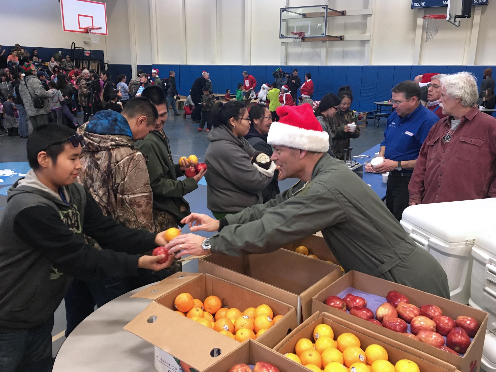 Commander of Alaskan Command, Lt. Gen. Kenneth Wilsbach, hands out fruit to an Akiachak student during Operation Santa Claus, Dec. 3. 2016. This year marked the 60th Anniversary of the Alaska National Guard community relations program. Guardsmen provide logistics and air support, delivering holiday cheer and gifts to rural Alaskan villages. (U.S. Air National Guard photo by Lt. Col. Candis Olmstead)