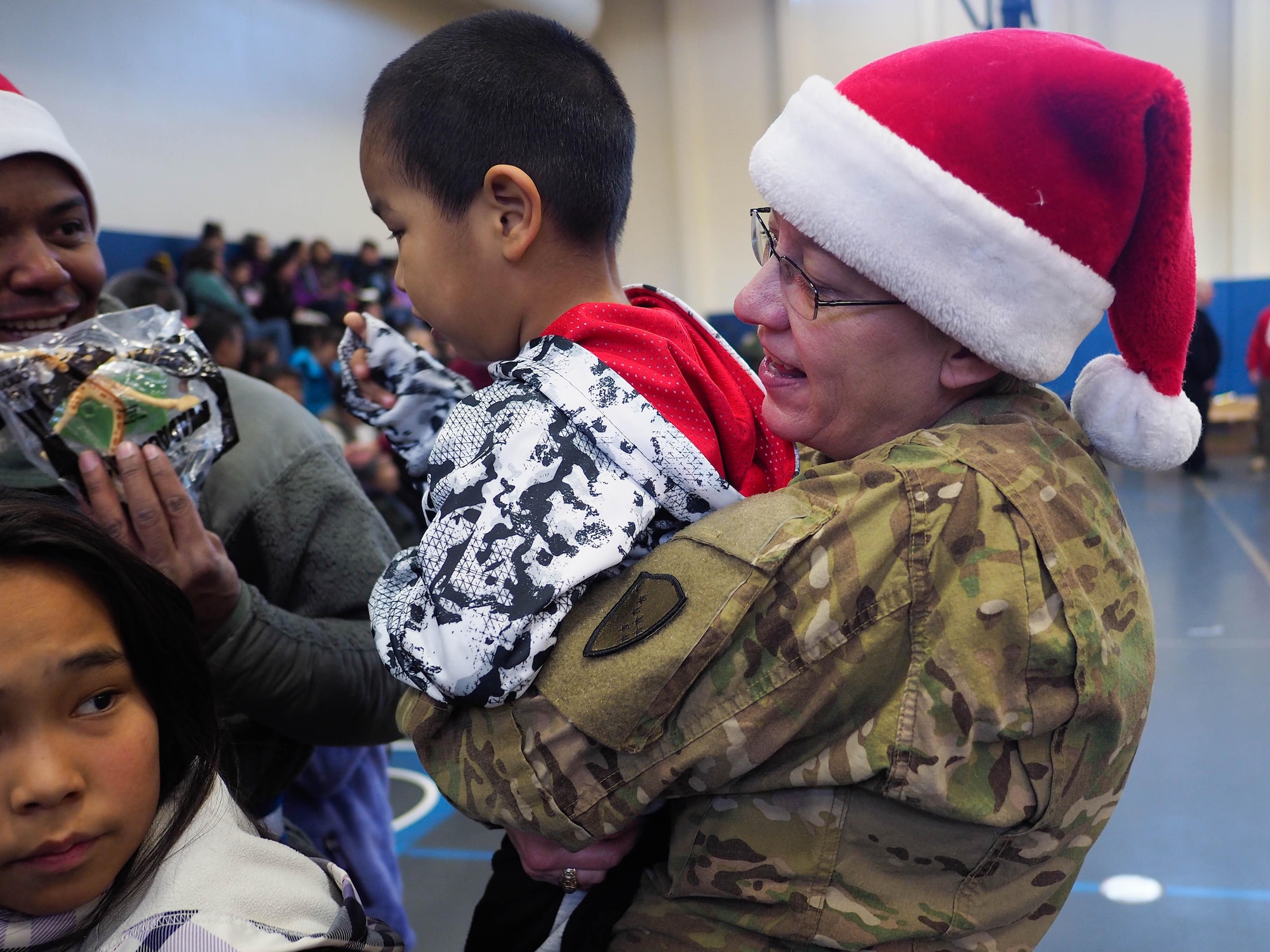 U.S. Army National Guard Brig. Gen. Laurie Hummel, adjutant general of the Alaska National Guardl, helps 4-year-old Angelo Pasitnak receive presents from the general's fellow Guardsmen, Dec. 3, 2016, at Akiachak School in Western Alaska. The gifts were distrubted to Akiachak residents as part of Operation Santa Claus. (U.S. Army National Guard photo by Sgt. David Bedard)