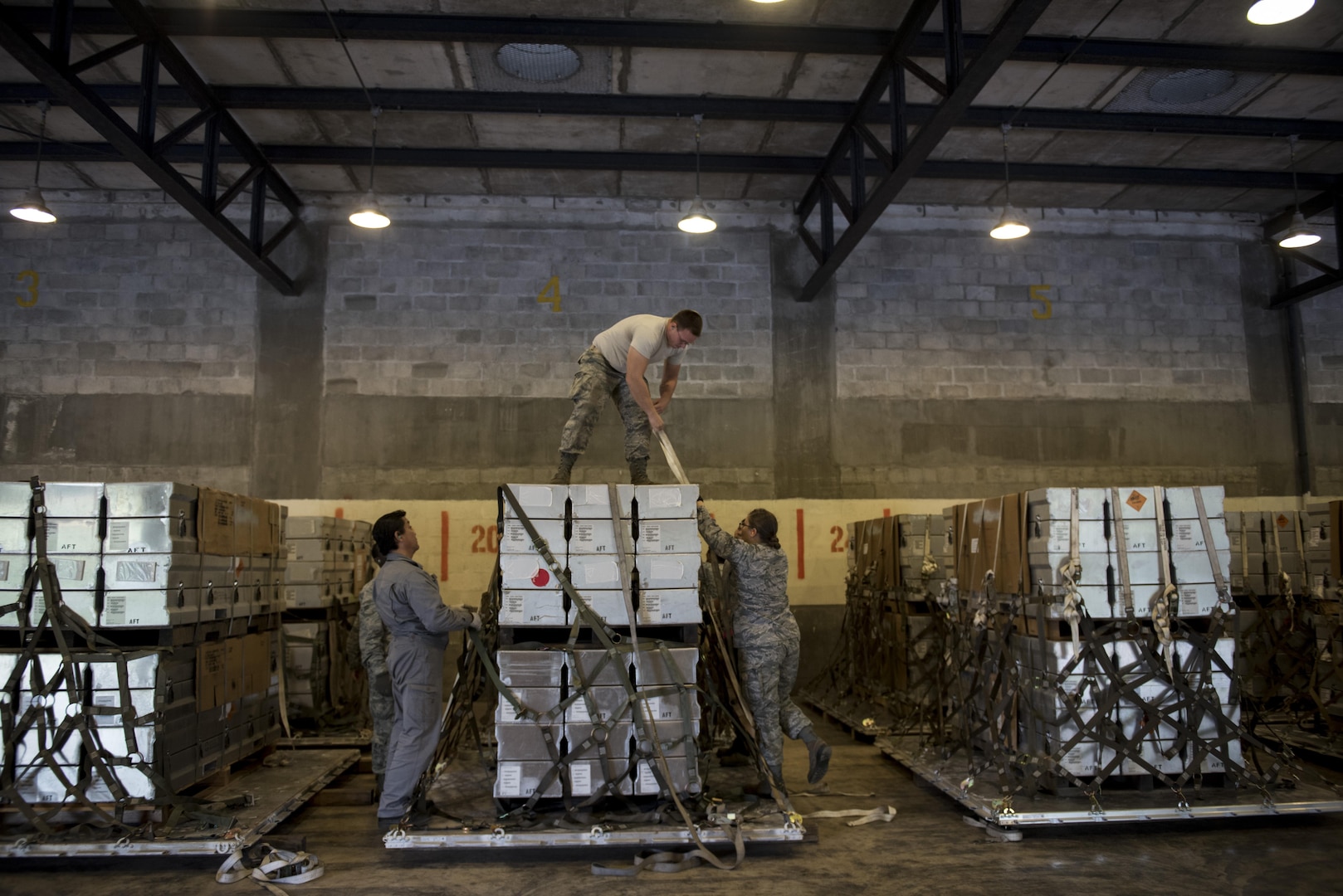 U.S. Air Force Airmen tie down and secure munitions to pallets during a Tactical Ammunition Rapid Response Package exercise Dec. 6, 2016, at Kadena Air Base, Japan. The TARRP exercise simulates how the squadron would rapidly prepare munition packages for transport downrange in times of war. (U.S. Air Force photo by Senior Airman Omari Bernard/Released)