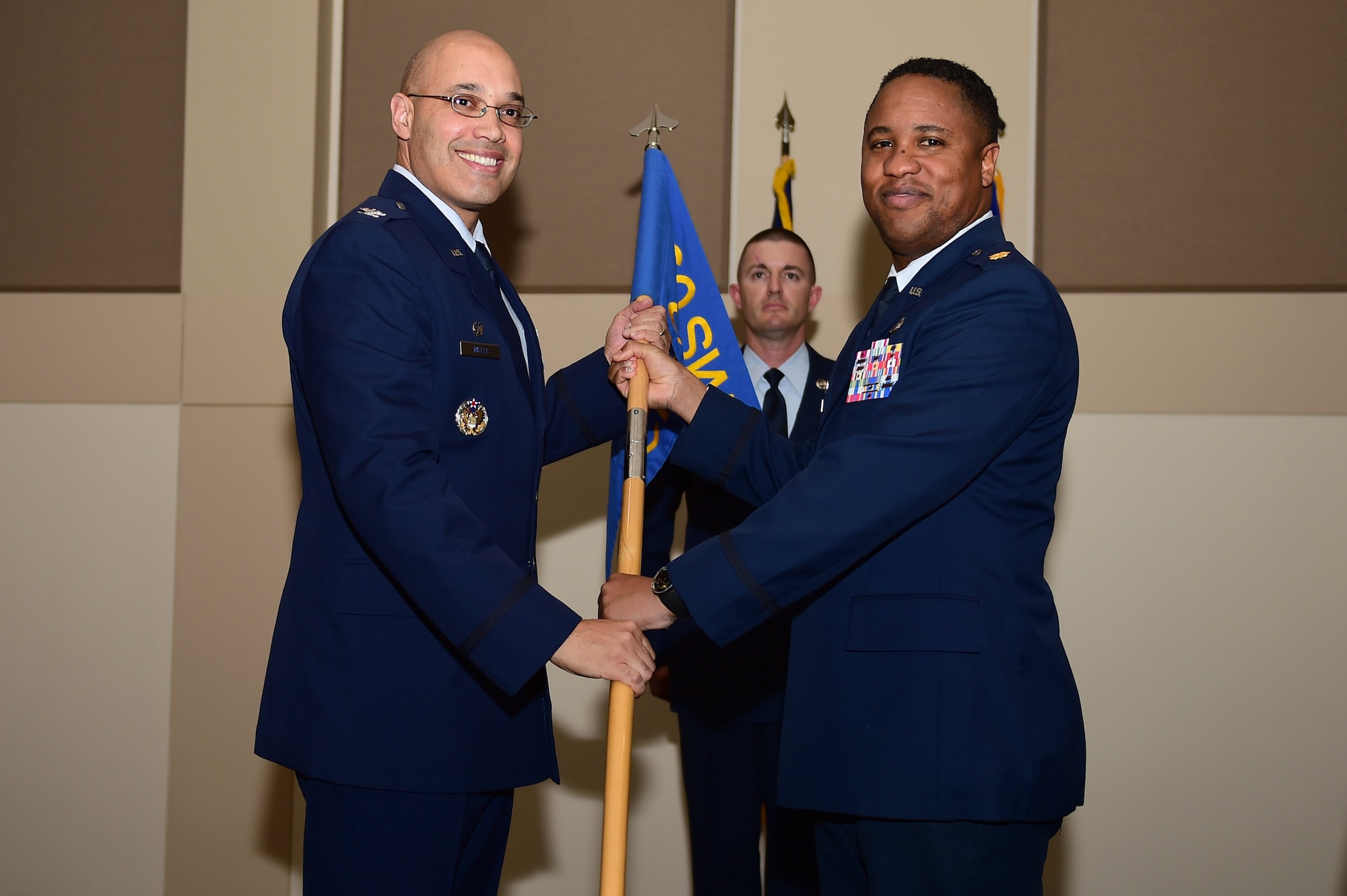 Maj. Douglass Eagleton, 460th outgoing Comptroller Squadron commander, relinquishes the CPTS guidon to Col. David Miller Jr., 460th Space Wing commander, Dec. 12, 2016, during the change of command ceremony on Buckley Air Force Base, Colo. A change of command ceremony represents the formal transfer of responsibility from an outgoing commander to their successor. (U.S. Air Force photo by Airman Jacob Deatherage/Released)