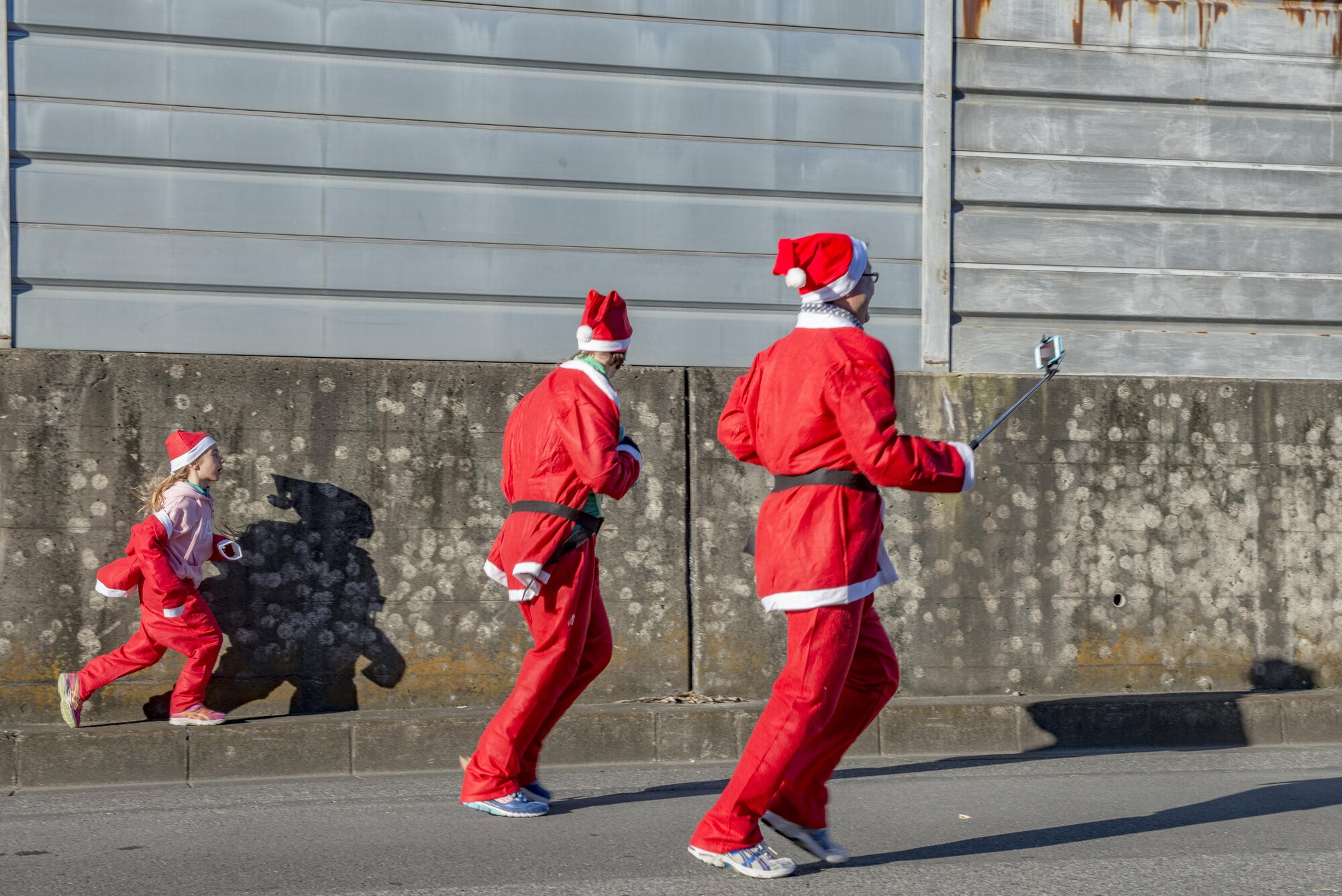 Participants encourage a child to run during Santa Shuffle 5K Fun Run Dec. 10, 2016, at Yokota Air Base, Japan. The event consisted of over 50 participants who were provided with Santa hats and outfits from the Yokota Striders. (U.S. Air Force photo by Airman 1st Class Donald Hudson/Released)