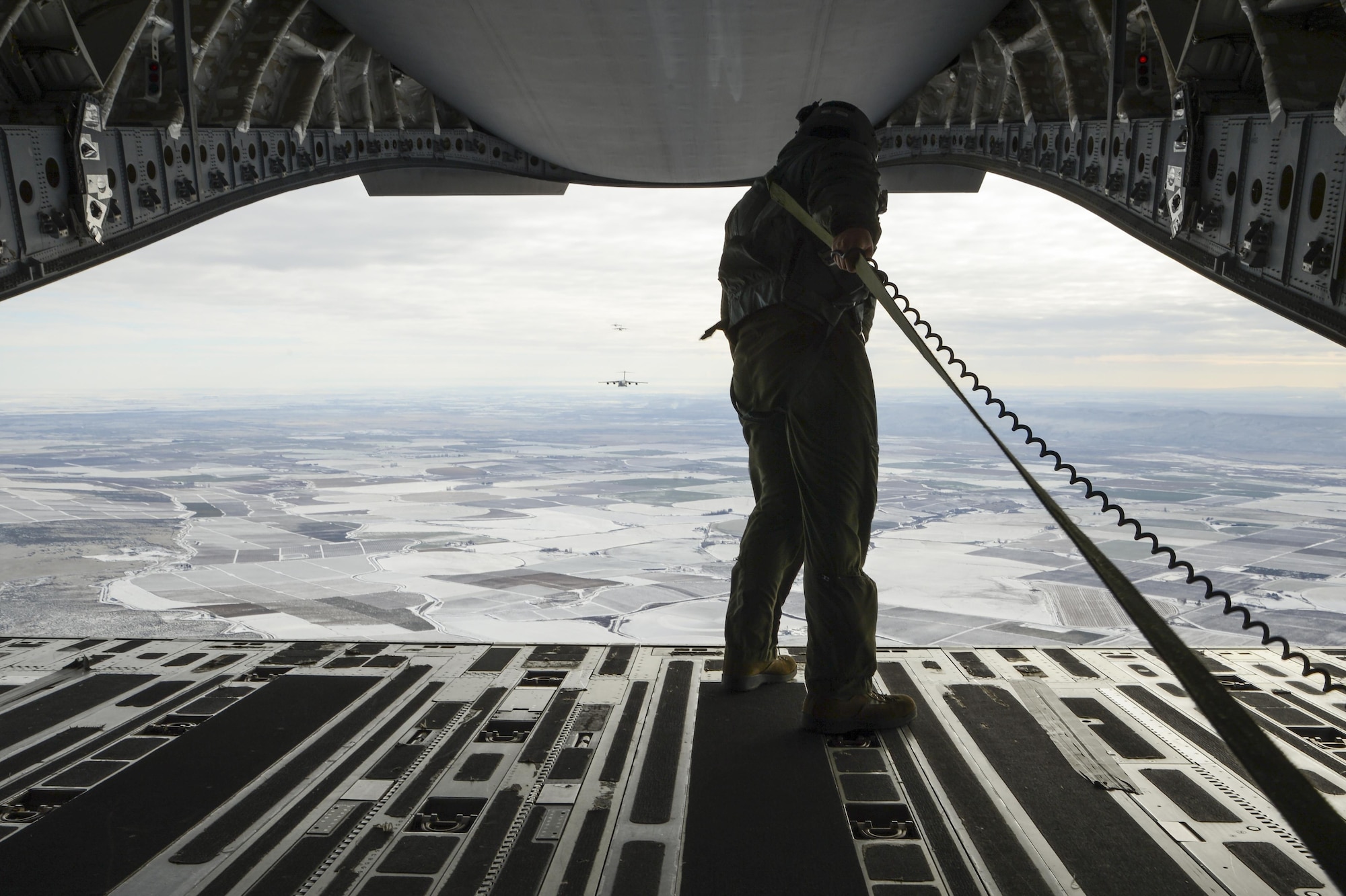 Staff Sgt. Brock Wranik, 62nd Operations Support Squadron loadmaster, looks on as a formation of six C-17 Globmaster IIIs prepare an airdrop over Rainier Drop Zone near Moses Lake, Wash., during the Rainier War exercise Dec. 7, 2016. The airdrop fulfilled one of the objectives of the exercise, which was to resupply members of the Army’s 7th Infantry Division with equipment and supplies. (U.S. Air Force photo/Tech. Sgt. Sean Tobin)