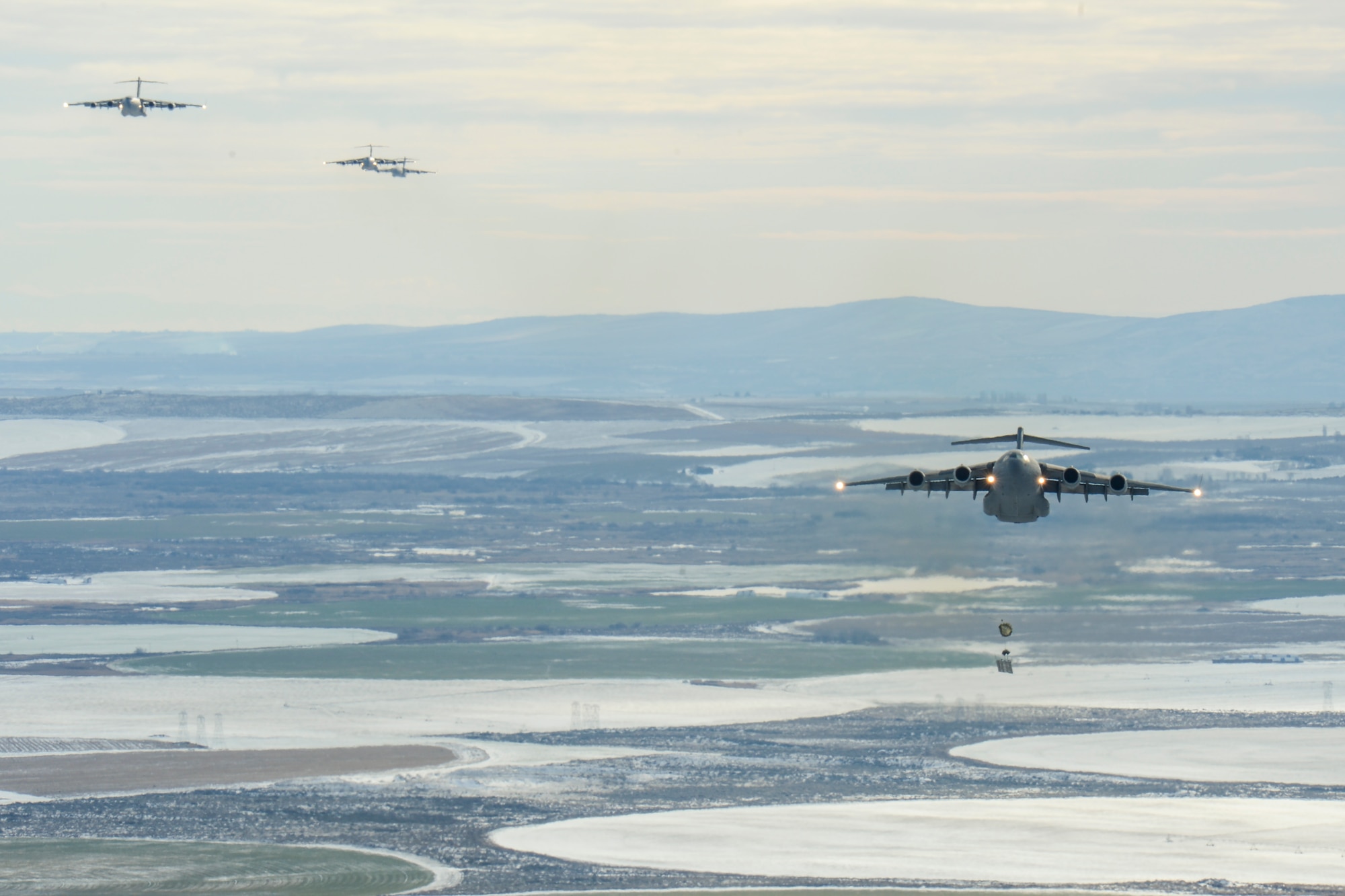 A formation of C-17 Globemaster III aircraft perform an airdrop Dec. 7, 2016, over Rainier Drop Zone near Moses Lake, Wash. The airdrop resupplied the Army’s 7th Infantry Division, which was one of the objectives of the Rainier War large-formation exercise, hosted by the 62nd Airlift Wing at Joint Base Lewis-McChord, Wash. (U.S. Air Force photo/Tech. Sgt. Sean Tobin)