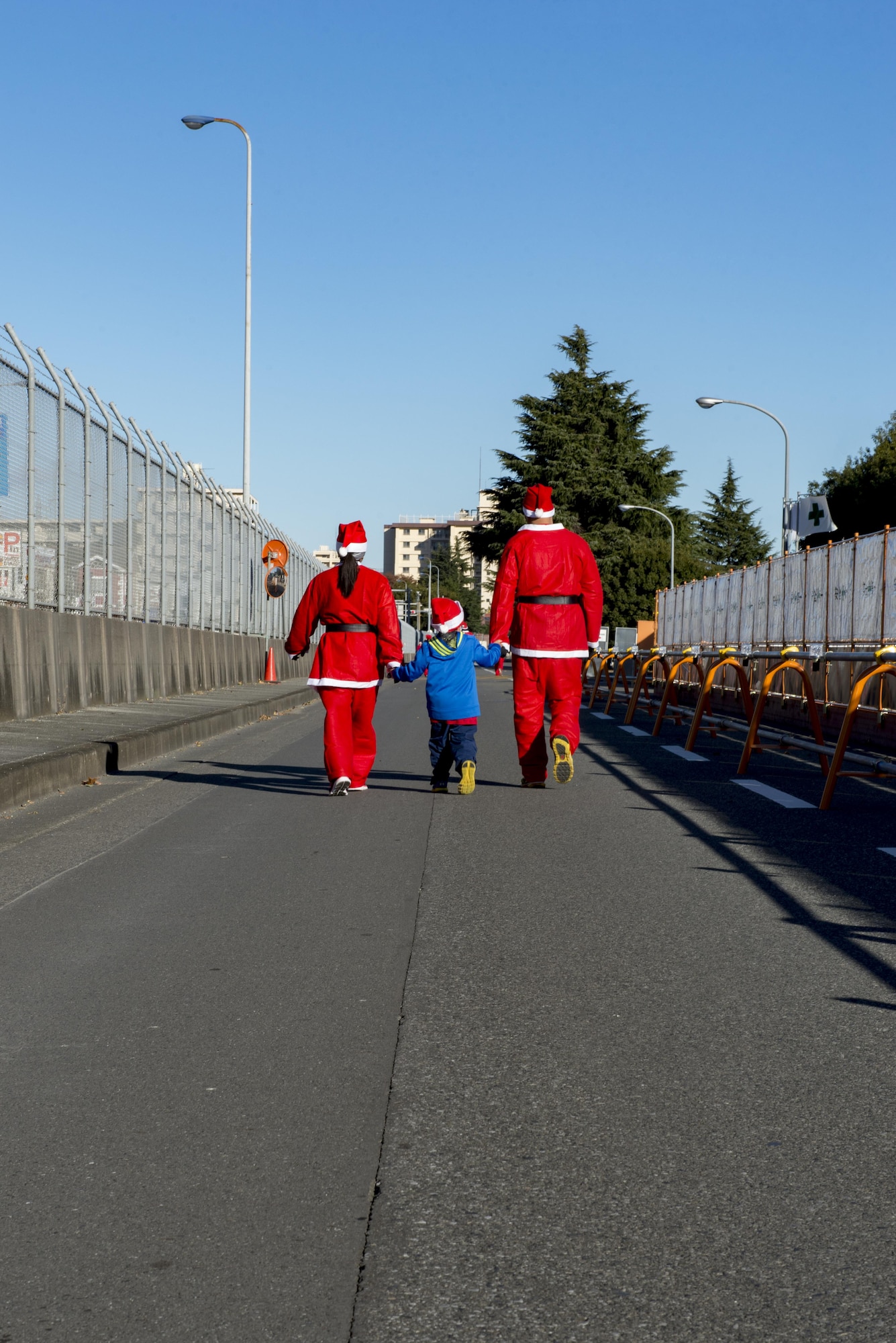 Participants walk with a child during the Santa Shuffle 5K Fun Run Dec. 10, 2016, at Yokota Air Base, Japan. Volunteers with the Yokota Striders running club organized the event to promote running and a healthy lifestyle. (U.S. Air Force photo by Airman 1st Class Donald Hudson/Released)