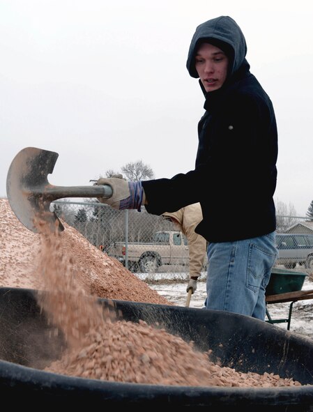 Airman 1st Class Nathan Tonden, an intel analyst assigned to the 89th Attack Squadron, pours gravel into a wheel barrel while volunteering with Habitat for Humanity in Rapid City, S.D., Dec. 10, 2016. Habitat for Humanity partners with people in communities all over the world to help build or improve a place they can call home. (U.S. Air Force photo by Airman 1st Class Donald C. Knechtel)
