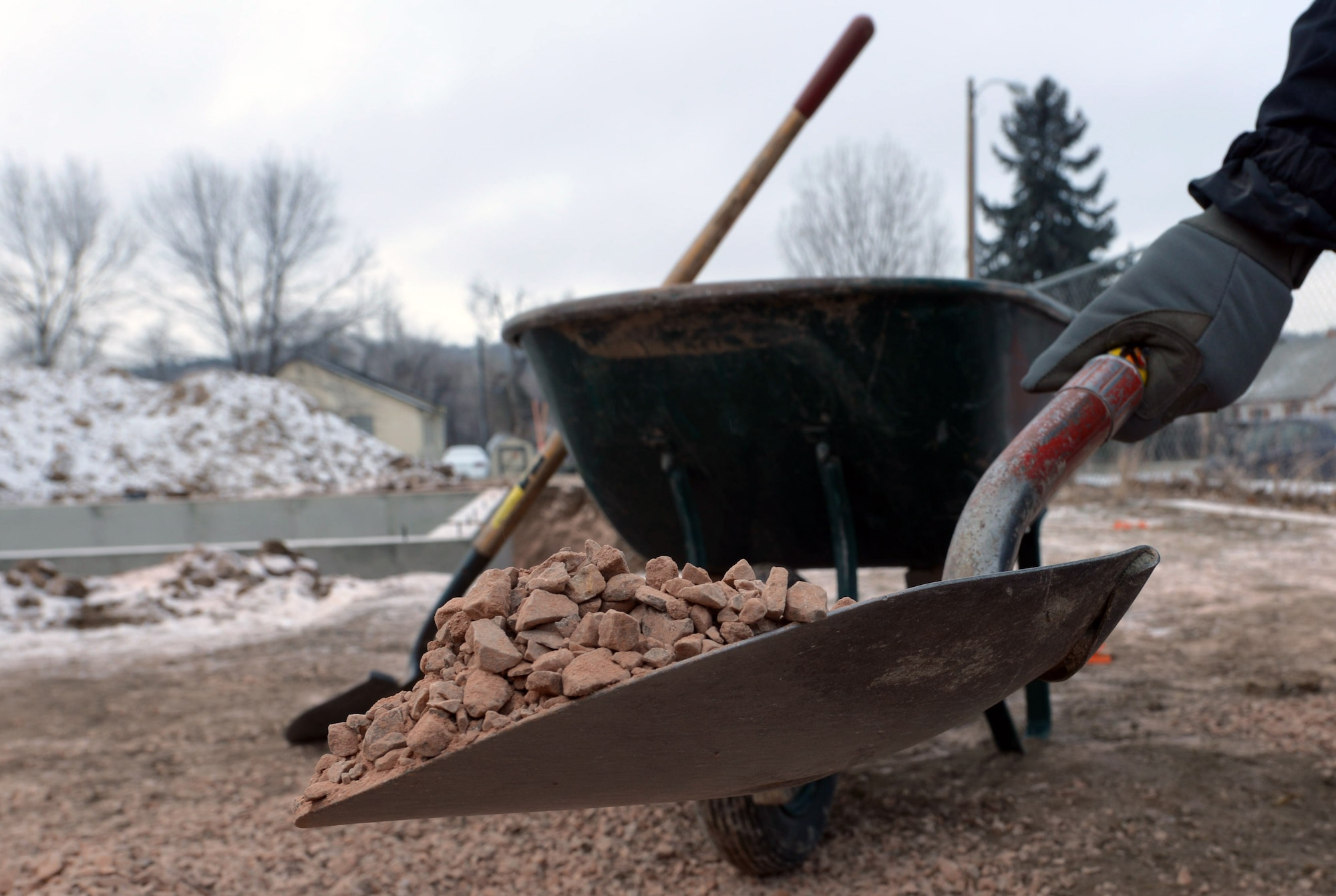 Senior Airman Shaquille Robinson, an intel analyst assigned to the 89th Attack Squadron, shovels gravel into a wheel barrel while volunteering for Habitat for Humanity in Rapid City, S.D., Dec. 10, 2016. According to Habitat for Humanity part of their mission is to bring people together to build not only homes, but communities and hope as well. (U.S. Air Force photo by Airman 1st Class Donald C. Knechtel)