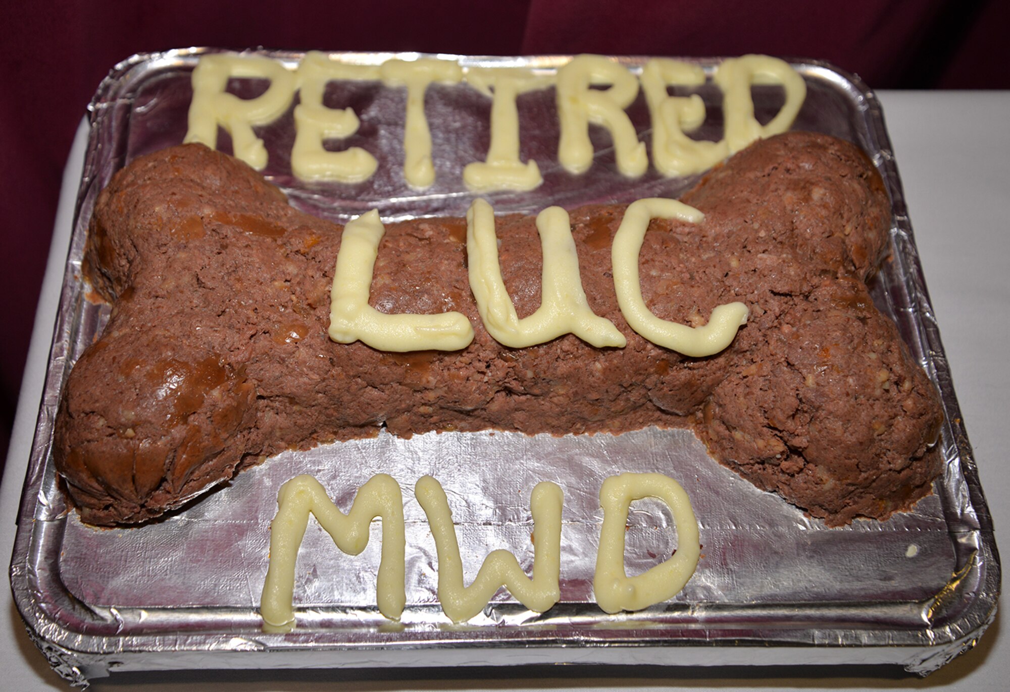 A special dog-food cake was made for Luc, former military working dog with the 100th Security Forces Squadron, for his retirement ceremony Dec. 12, 2016, on RAF Mildenhall, England. Luc has served seven-and-a-half years – more than 50 “dog years” -- with the U.S. Air Force and has been adopted by the family who are part of his former squadron. (U.S. Air Force photo by Karen Abeyasekere)