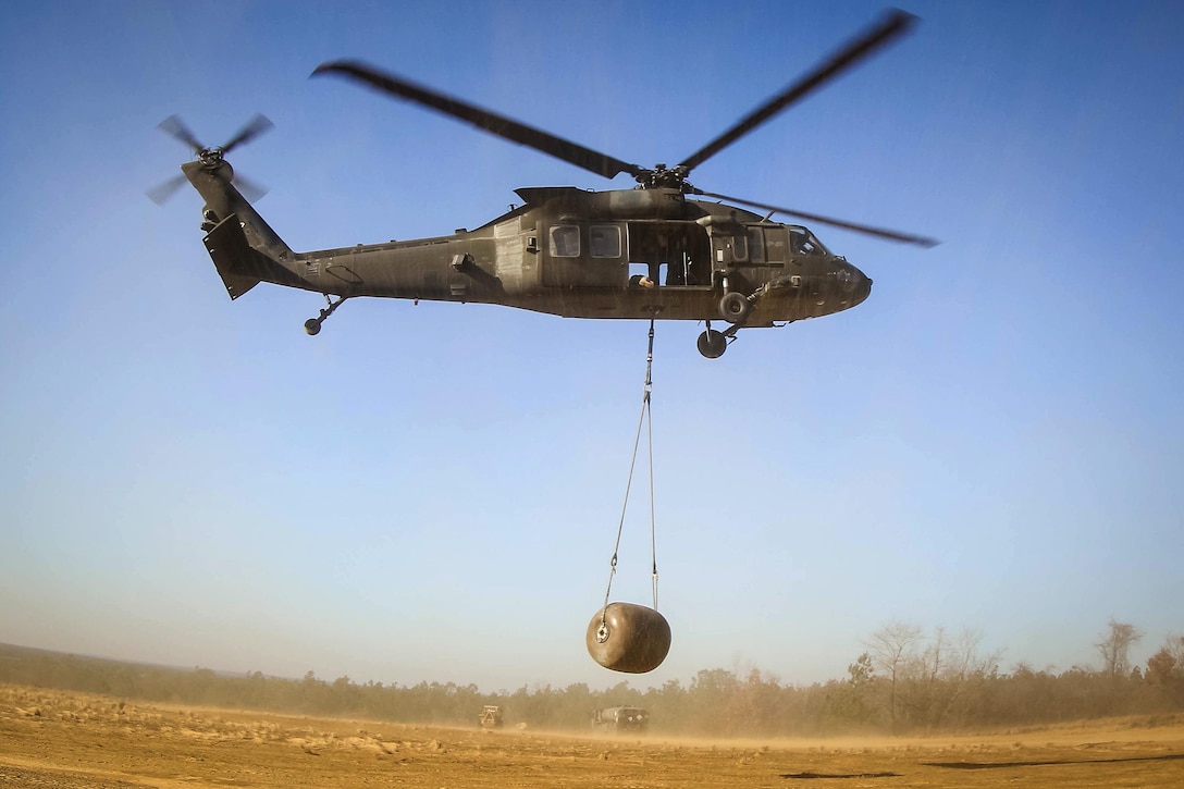 A UH-60 Black Hawk helicopter takes off carrying a water blivet during slingload training at Fort Bragg, N.C., Dec. 7, 2016. Army photo by Sgt. Steven Galimore