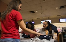 Master Sgt. Erreka Coleman, left, 450th Intelligence Squadron distributed ground system cyber liaison officer, and Master Sgt. Laylanny Johnson, 450th IS weapons and tactics flight chief, hand out t-shirts for the participants of the Winter Special Olympics at Vogelweh Military Complex, Germany, Dec. 2, 2016. Coleman and Johnson volunteered to help at the Olympics as a part of their squadron’s 2nd annual service day. (U.S. Air Force photo by Senior Airman Tryphena Mayhugh)