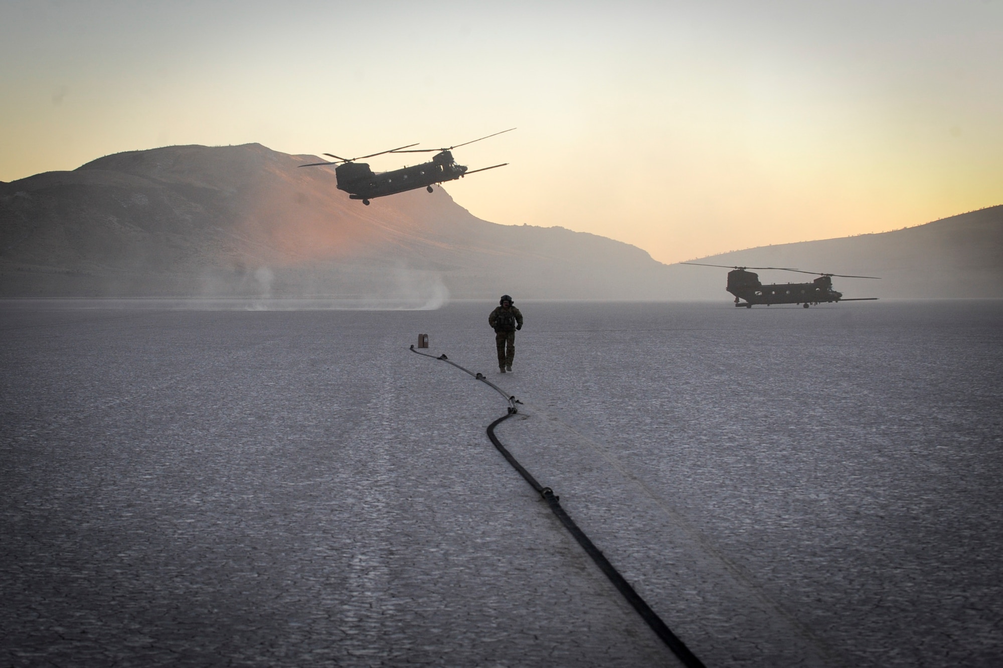 U.S. Army flying crew chief assigned to the 160th Special Operations Aviation Regiment sets up the forward area refueling point with two MH-47 aircraft at the Delmar desert landing strip, Nev., Dec. 2. The forward area refueling site was enabled by special tactics Airmen providing security at the landing zone and was conducted within a highly contested environment with an AC-130U providing close air support. (U.S. Air Force photo by Major Richie Harr)