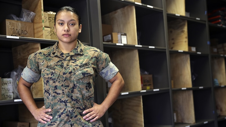Sgt. Angie Novoa, a warehouse chief with Special Purpose Marine Air-Ground Task Force Crisis Response-Africa, stands in front of shelves in her warehouse on Naval Air Station Sigonella, Italy, Oct. 28, 2016.  Novoa was awarded the non-commissioned officer of the quarter for her exemplary work in and out of the supply shop while deployed with SPMAGTF-CR-AF.