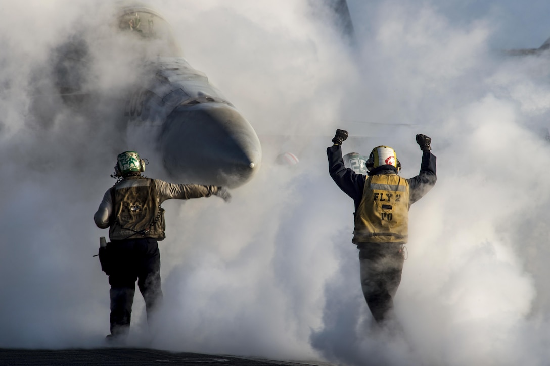 Navy Petty Officer 1st Class Jeremy Parrish signals to the pilot of an F/A-18E Super Hornet on the flight deck of the USS Dwight D. Eisenhower in the Mediterranean Sea, Dec. 10, 2016. The Hornet is assigned to Strike Fighter Squadron 86. The aircraft carrier is supporting U.S. national security interests in Europe. Navy photo by Petty Officer 3rd Class Nathan T. Beard