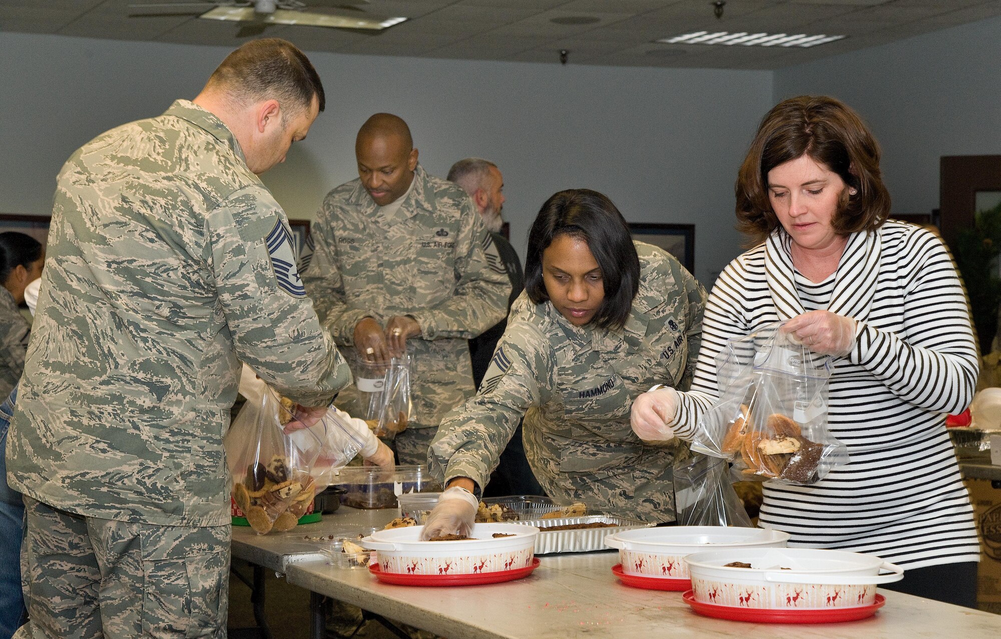 Chief Master Sgt. Brian Schexnider, 436th Logistics Readiness Squadron fuels superintendent; Chief Master Sgt. Darryl Ross, 436th Force Support Squadron chief enlisted manager; Chief Master Sgt. Erica Hammond, 436th Medical Group superintendent; and Brooke Throckmorton, wife of Lt. Col. Charles Throckmorton, 9th Airlift Squadron commander, place a dozen donated cookies in each plastic bag during the annual holiday cookie drop Dec. 12, 2016, at the 9th AS on Dover Air Force Base, Del. Volunteers packaged 540 dozen cookies for single, Team Dover Airmen living in the dormitories. (U.S. Air Force photo by Roland Balik)