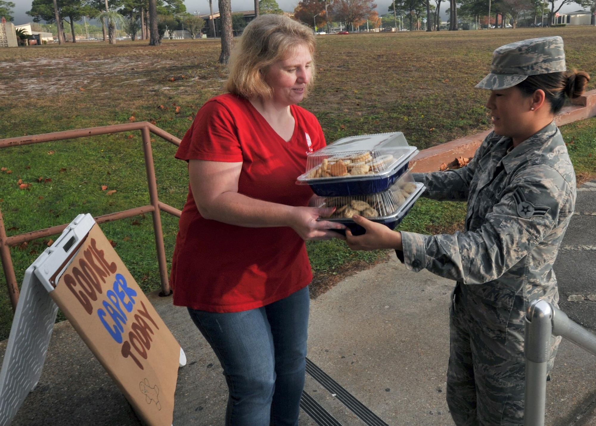 Regina Zick, Tyndall Spouses Club member, receives cookie donations from Airman 1st Class Sara Dugger, 325th Force Support Squadron services journeyman, during the Cookie Caper preparation at the thrift shop on Tyndall Air Force Base, Fla., Dec. 12, 2016. Volunteers donated more than 650 dozen cookies for the event. (U.S. Air Force photo by Senior Airman Ty-Rico Lea/Released)