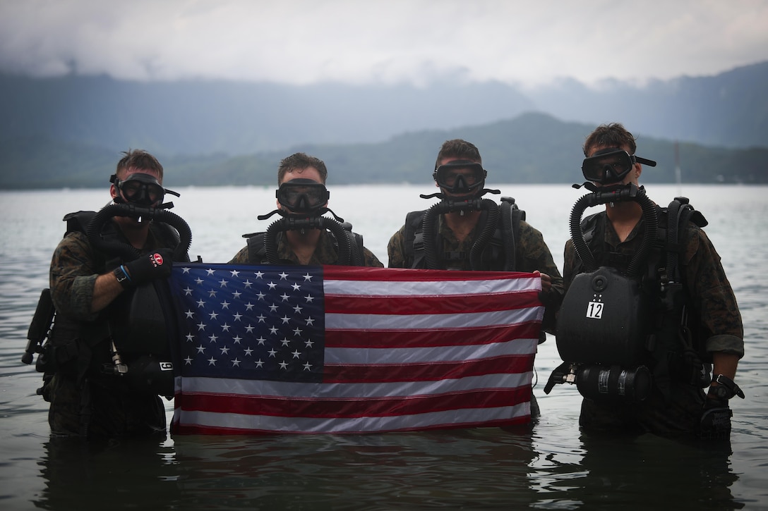 Marines with 4th Force Reconnaissance Battalion pose with the American flag during dive operations in Kaneohe Bay, Hawaii, Dec. 9, 2016. The mission of Marine Corps Base Hawaii is to provide facilities, programs and services in direct support of units, individuals and families in order to enhance and sustain combat readiness for all operating forces and tenant organizations aboard MCB Hawaii. (U.S. Marine Corps photo by Cpl. Aaron S. Patterson/Released)