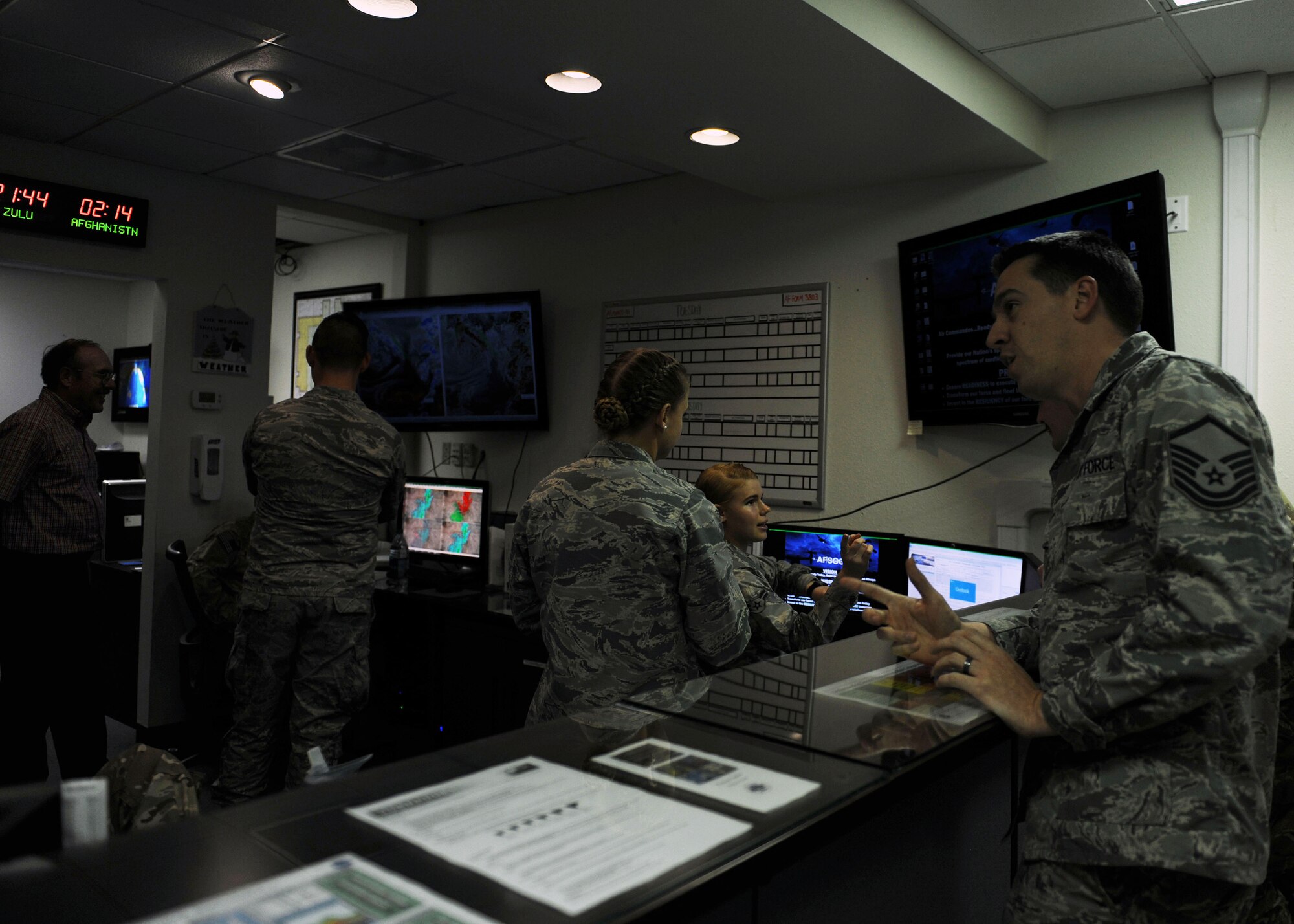 Members of the 27th Special Operations Support Squadron talk with one another during an afternoon meeting at base operations, Nov. 21, 2016 at Cannon Air Force Base, N.M. Weather forecasters at Cannon are responsible for creating forecasts pertinent to day-to-day base operations, flight operations, and contingency operations from installation to installation. (U.S. Air Force photo by Staff Sgt. Whitney Amstutz/released)