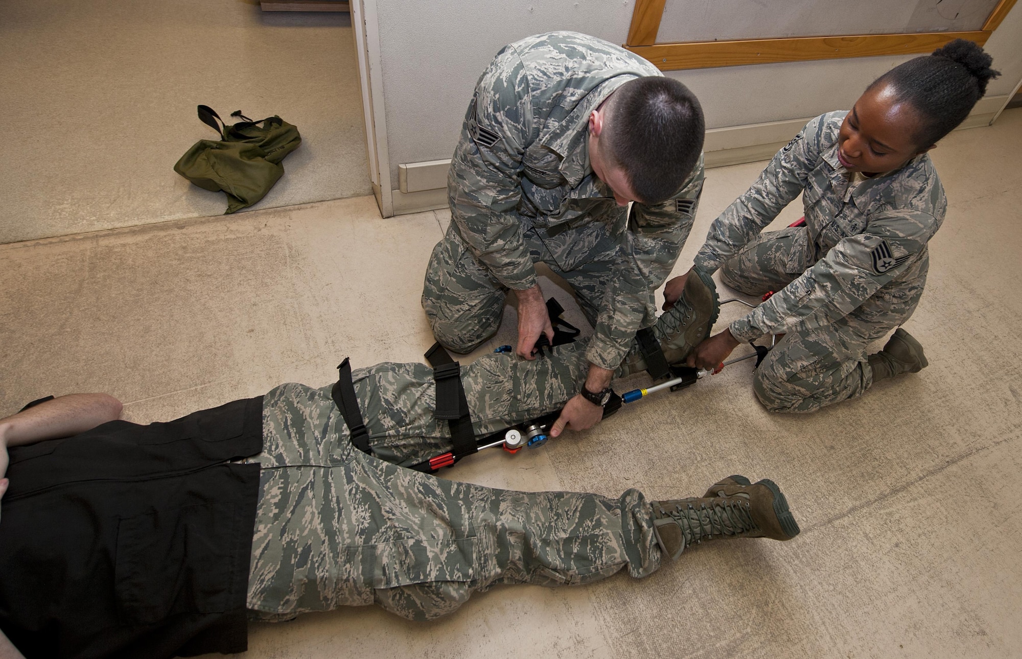 (From left) Senior Airman Robert Moon, 5th Medical Operations Squadron aerospace medical technician, and Staff Sgt. Afsatu Kamara, 5 MDOS emergency medical technician, connect a traction splint to a simulated patient at Minot Air Force Base, N.D., Dec. 1, 2016. Ambulance services Airmen use traction splints to reduce pain, realign limbs and minimize a patient’s vascular and neurological complications. (U.S. Air Force photo/Airman 1st Class Jonathan McElderry)