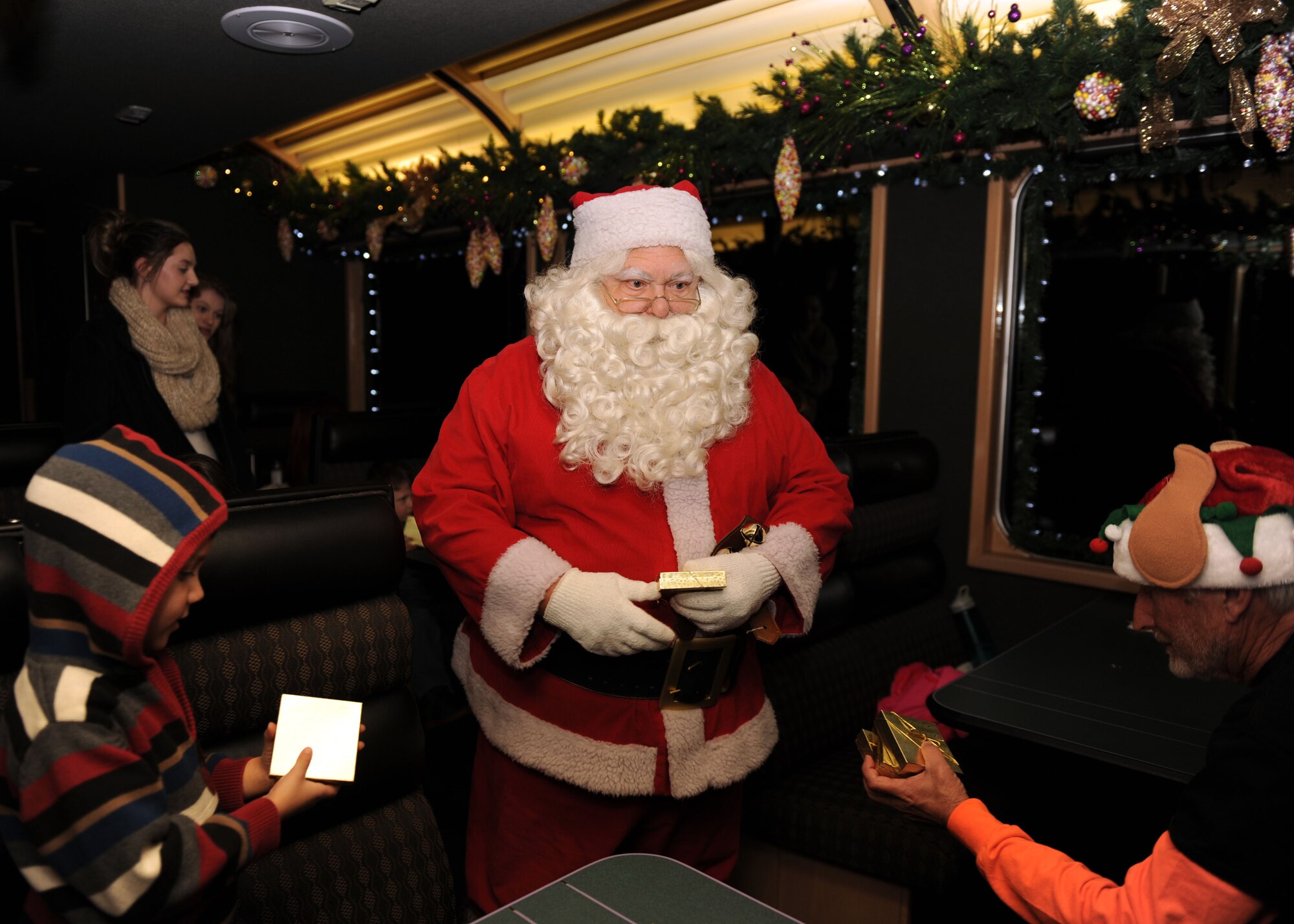 Santa Claus delivers presents to children aboard the Holiday Express, Dec. 1, 2016, in Clovis, N.M. For nine consecutive years, the BNSF Railway has invited service members and their loved ones aboard the Holiday Express to enjoy milk, cookies, and a visit from Santa Claus to show their appreciation. (U.S. Air Force photo by Staff Sgt. Whitney Amstutz/Released)