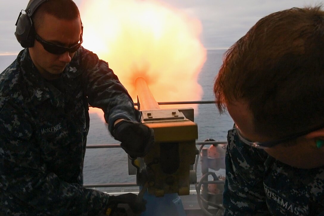 Navy Petty Officer 1st Class James Mckenzie, left, and Petty Officer 2nd Class Cody Christmas fire a 21-gun salute to mark the 75th anniversary of the attacks on Pearl Harbor, from the super structure of the amphibious assault ship USS Bataan in the Atlantic Ocean, Dec. 7, 2016. Navy photo by Seaman Evan Thompson