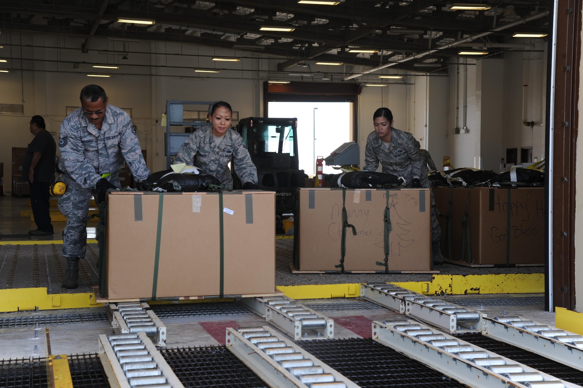 U.S. Air Force Tech. Sgt. Sinforoso Galindez, and Senior Airmen Daena Manaspit and Geralyn Lunod, air transportation specialists with the Air Force Reserve's 44th Aerial Port Squadron, push Christmas boxes in place as a part of the 65th Operation Christmas Drop at Andersen Air Force Base, Guam, Dec. 7, 2016. Operation Christmas Drop is the longest running humanitarian airlift operation in the history of the Department of Defense, impacting the lives of more than 20,000 islanders. The people of the Micronesian islands can expect to see service members aboard a C-130 Hercules drop a box, attached to a parachute, filled with rice, fish hooks, educational materials, clothing and toys. The 44th Aerial Port Squadron supports the 624th Regional Support Group's mission to deliver mission essential capability through combat readiness, quality management and peacetime deployments in the Pacific area of responsibility. (U.S. Air Force photo by Master Sgt. Theanne Herrmann)