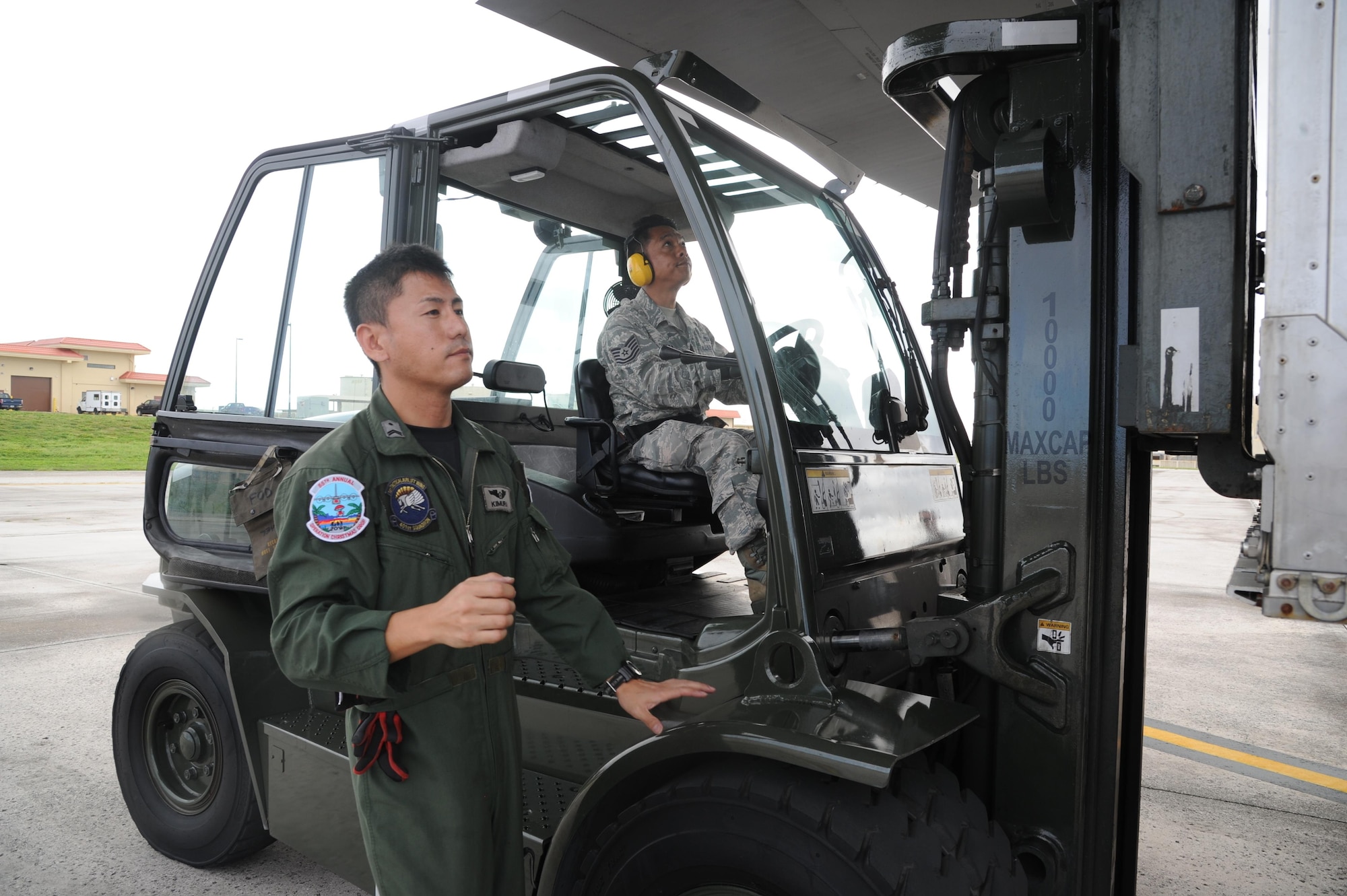 U.S. Air Force Tech. Sgt. Paul Diaz, right, an air transportation specialists for the Air Force Reserve's 44th Aerial Port Squadron, takes direction from Tech. Sgt. Takuya Kimura, Japanese Self Defense Force, while operating a 10K forklift to load a container onto their C-130 Hercules at Andersen Air Force Base, Guam, Dec. 8, 2016. Operation Christmas Drop is the longest running humanitarian airlift operation in the history of the Department of Defense, impacting the lives of more than 20,000 islanders. The people of the Micronesian islands can expect to see service members aboard a C-130 Hercules drop a box, attached to a parachute, filled with rice, fish hooks, educational materials, clothing and toys. The 44th Aerial Port Squadron supports the 624th Regional Support Group's mission to deliver mission essential capability through combat readiness, quality management and peacetime deployments in the Pacific area of responsibility. (U.S. Air Force photo by Master Sgt. Theanne Herrmann)